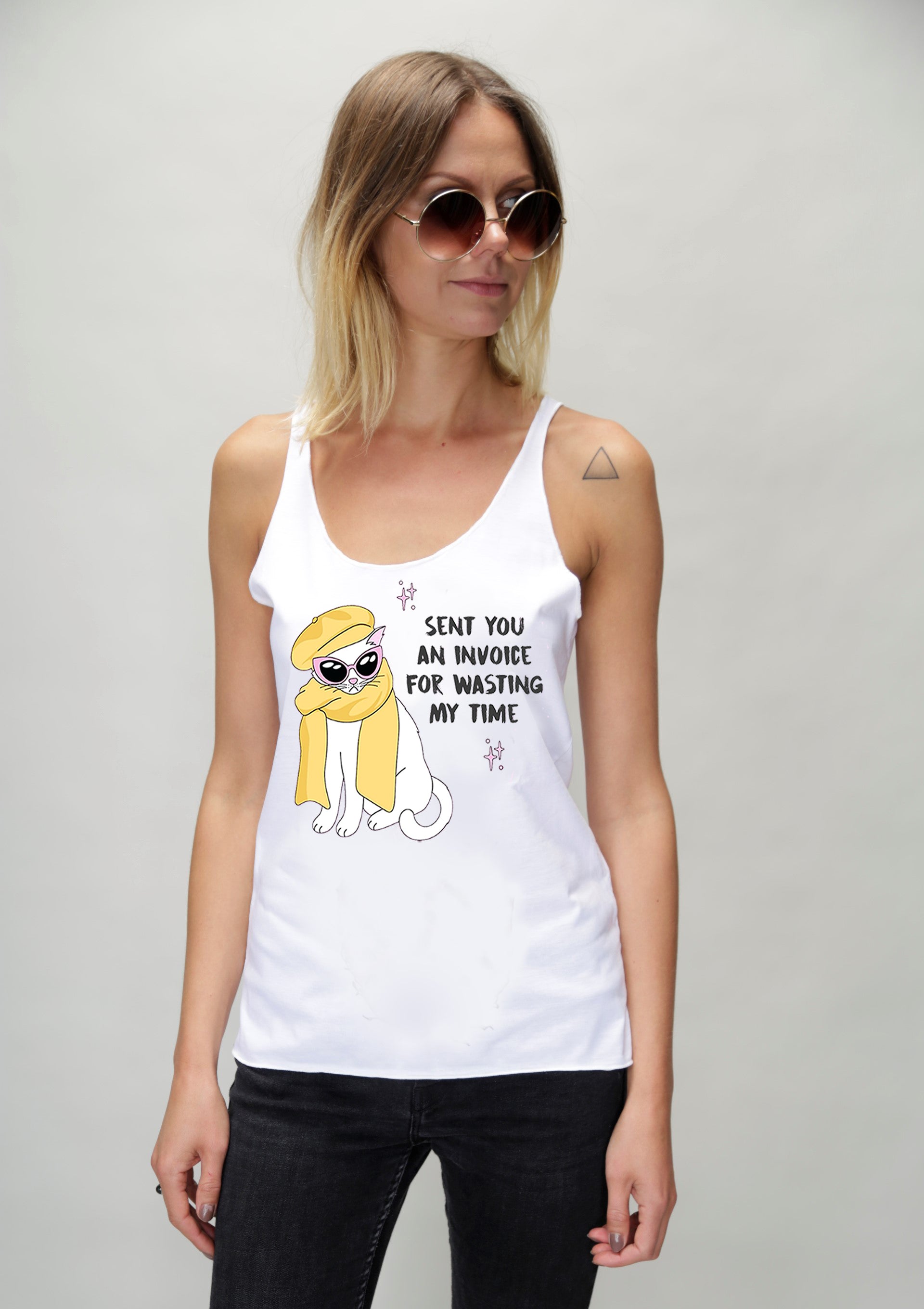 Woman wearing a white tank top with a graphic design on a plain background