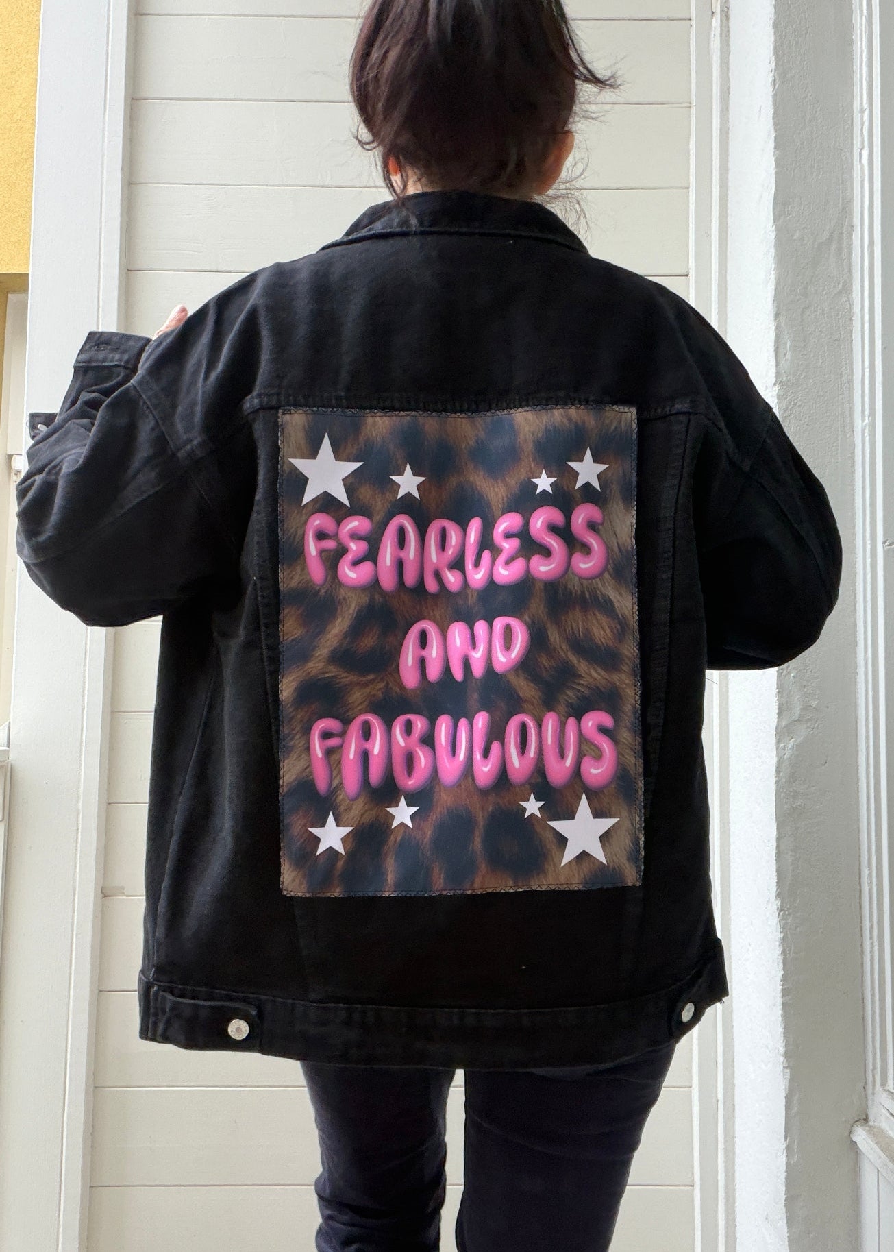 Person wearing a black jacket with 'Fearless and Fabulous' text on the back