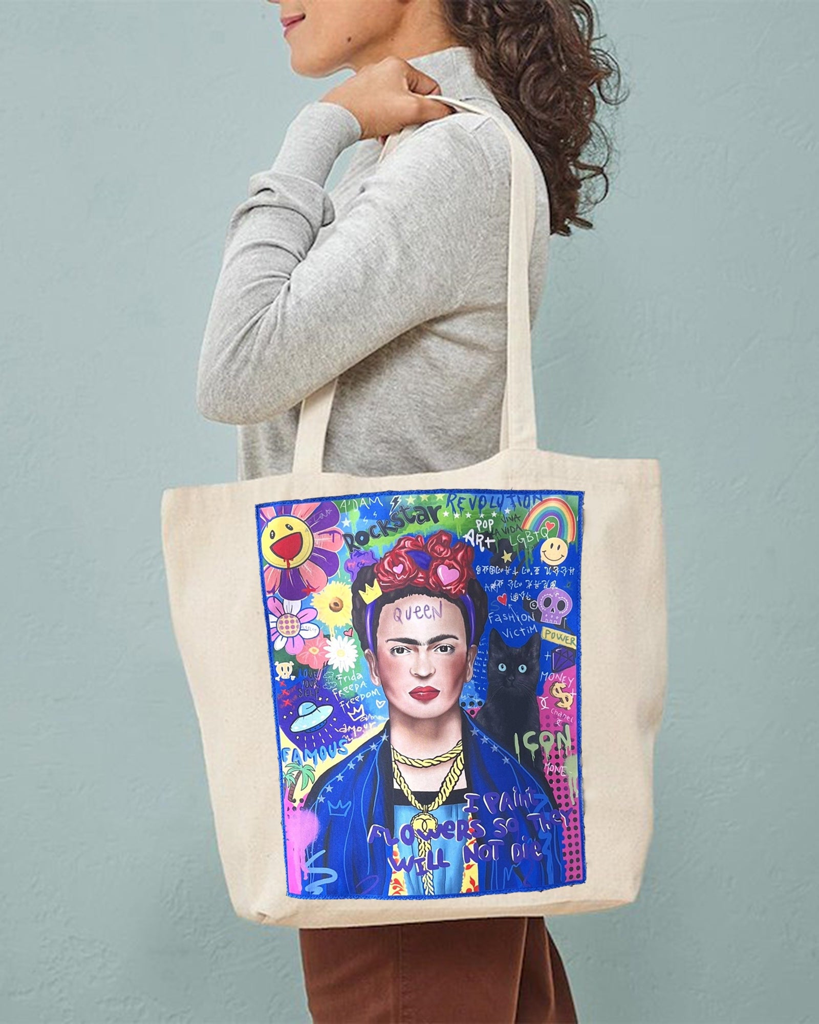 Person holding a tote bag with a colorful design of a famous artist on a plain background