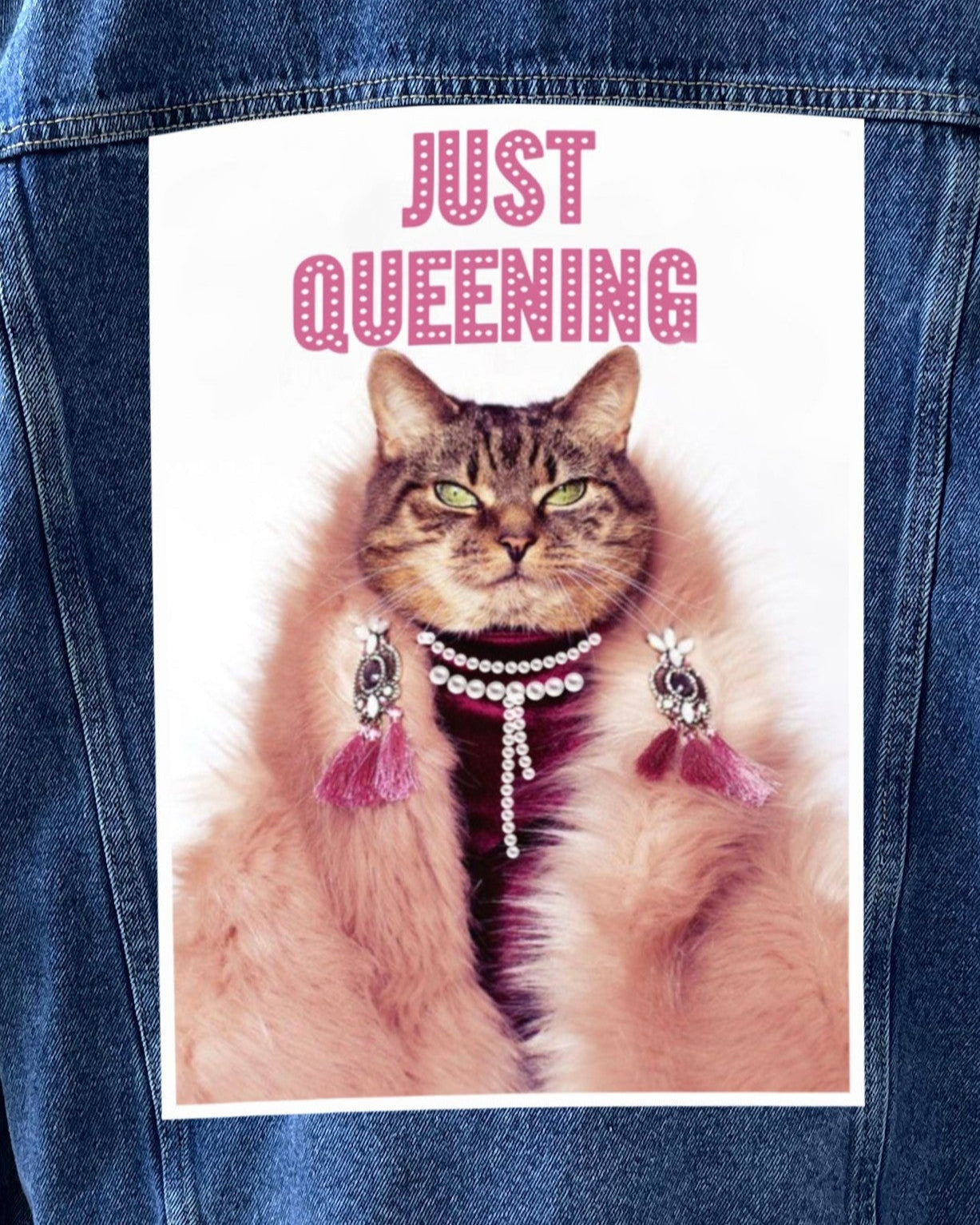 A sew-on canvas patch featuring an illustration of a cat with the text 'JUST QUEENING' on a denim background.
