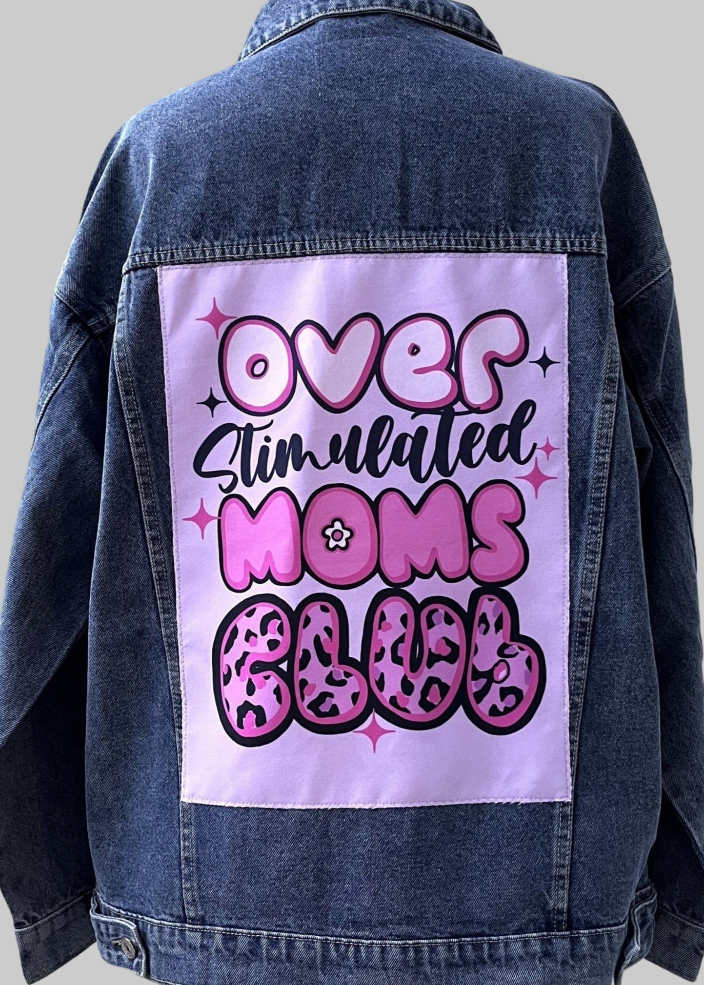Denim jacket with a graphic design on the back against a white background