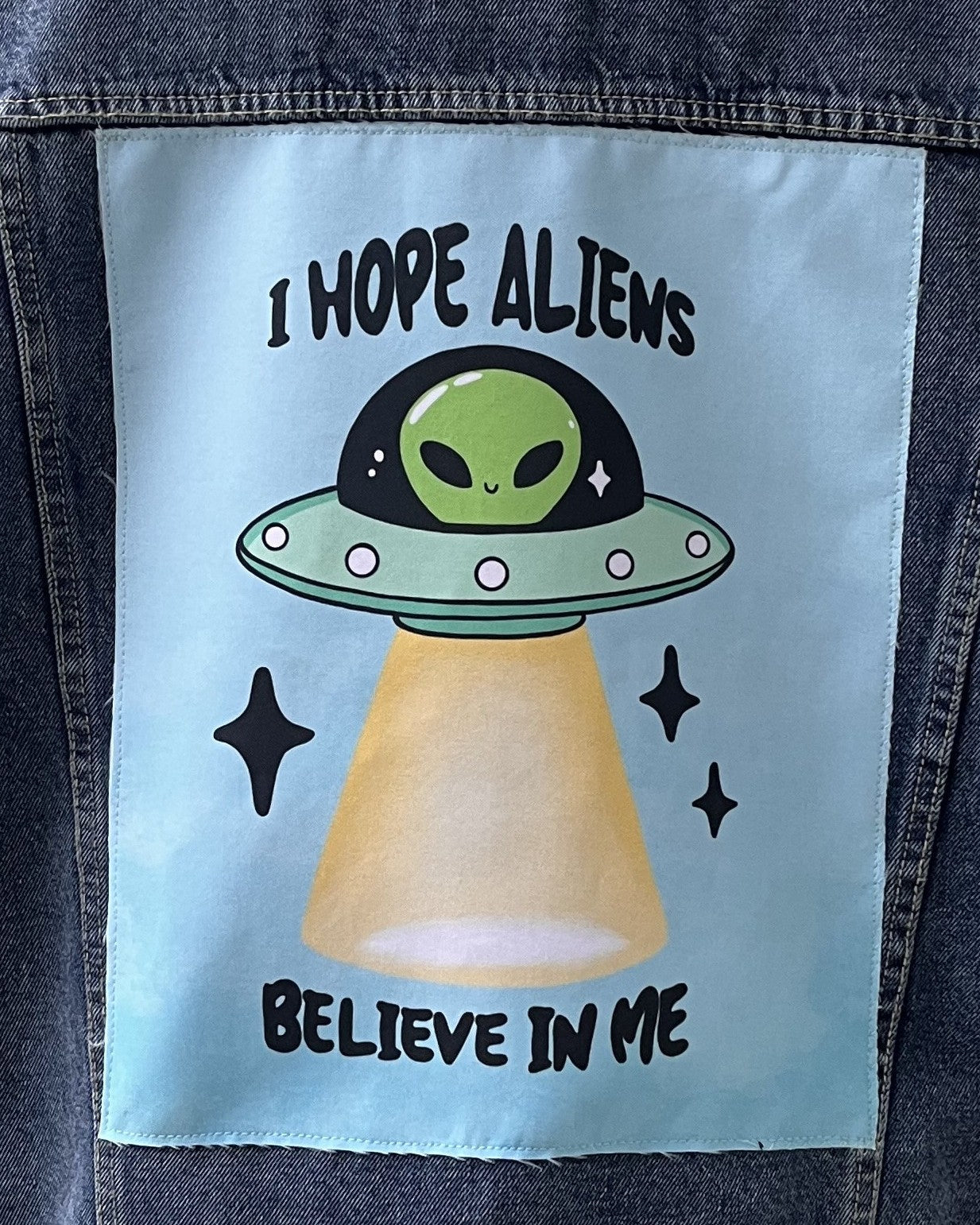 A patch featuring an alien in a flying saucer with the text 'I HOPE ALIENS BELIEVE IN ME' on a blue background.