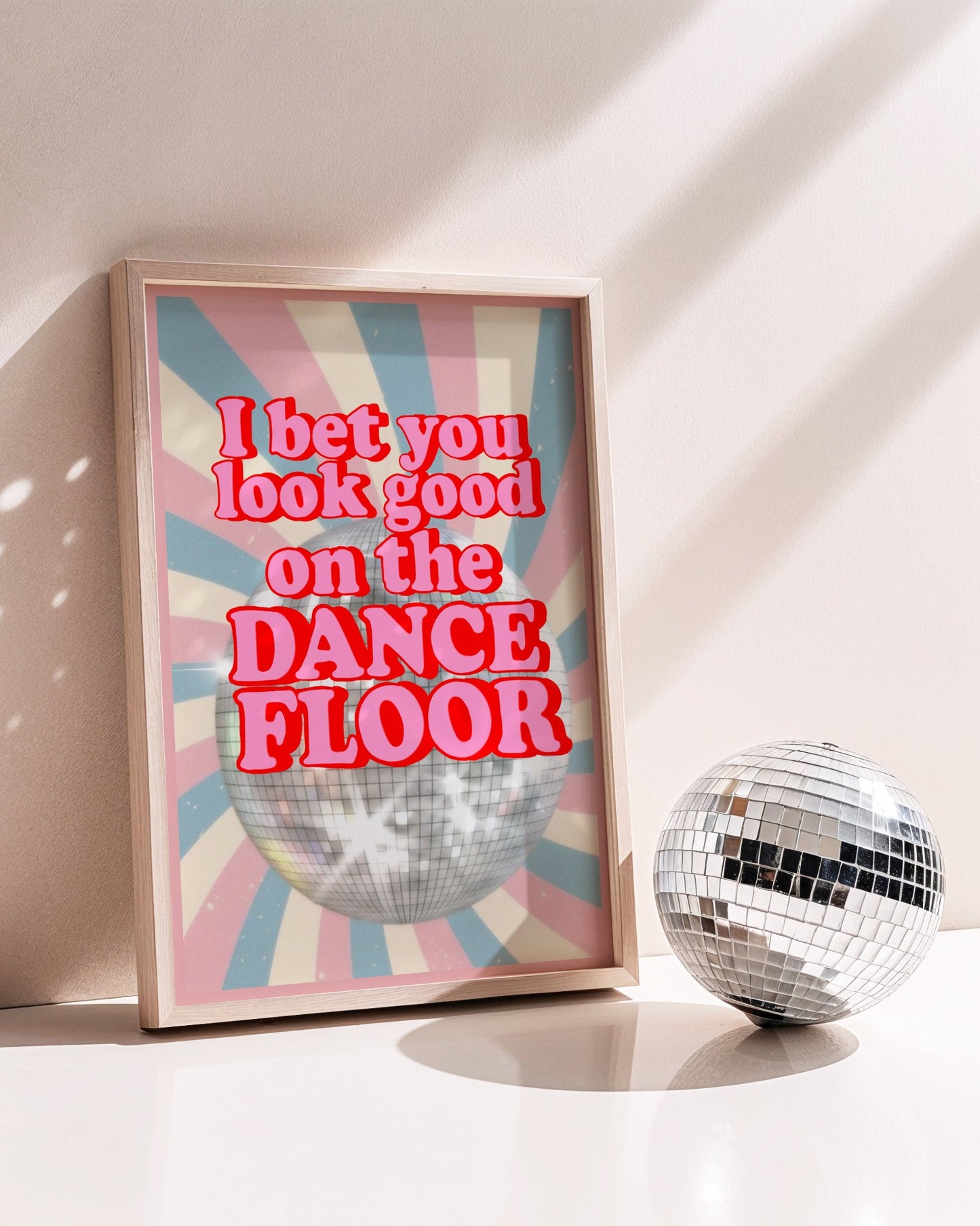 Framed artwork with 'I bet you look good on the dance floor' text next to a disco ball.