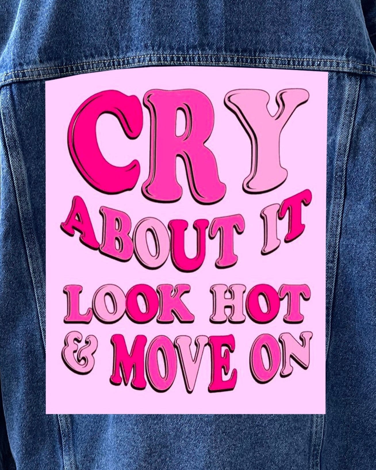 A denim jacket with a pink back patch featuring the text 'CRY ABOUT IT LOOK HOT & MOVE ON' in stylized lettering.