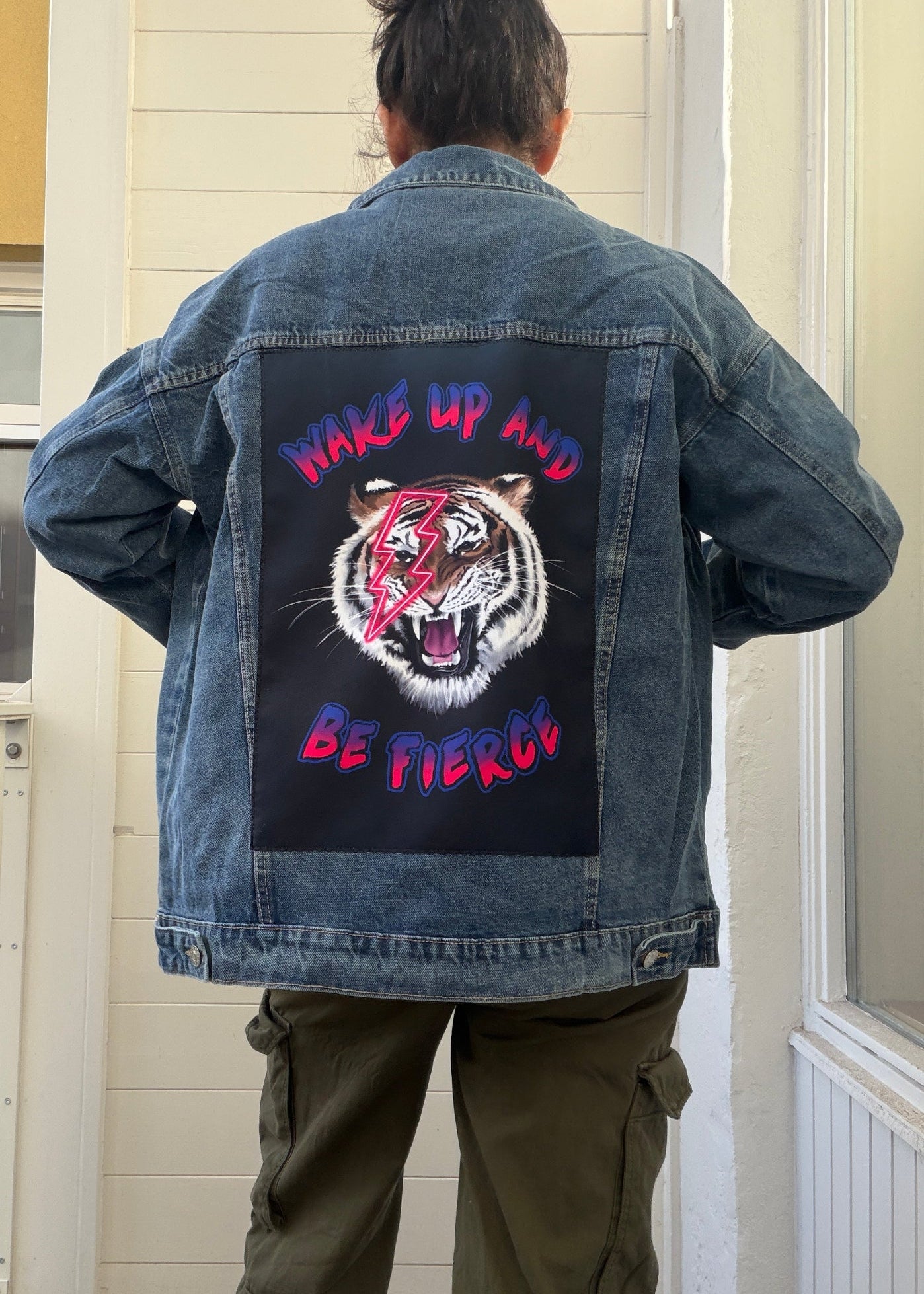 Person wearing a denim jacket with a graphic design and text on the back.