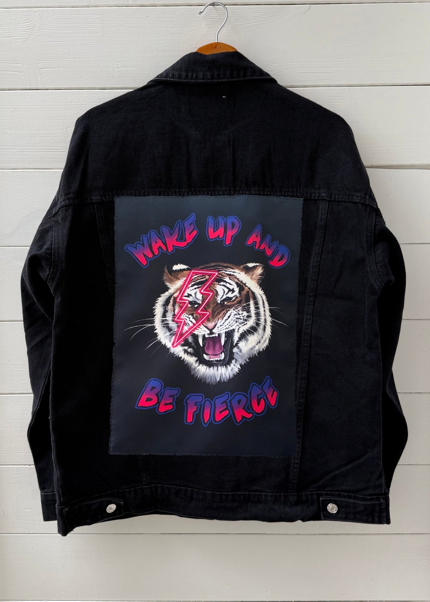 Black jacket with a graphic of a tiger and text on a wooden background
