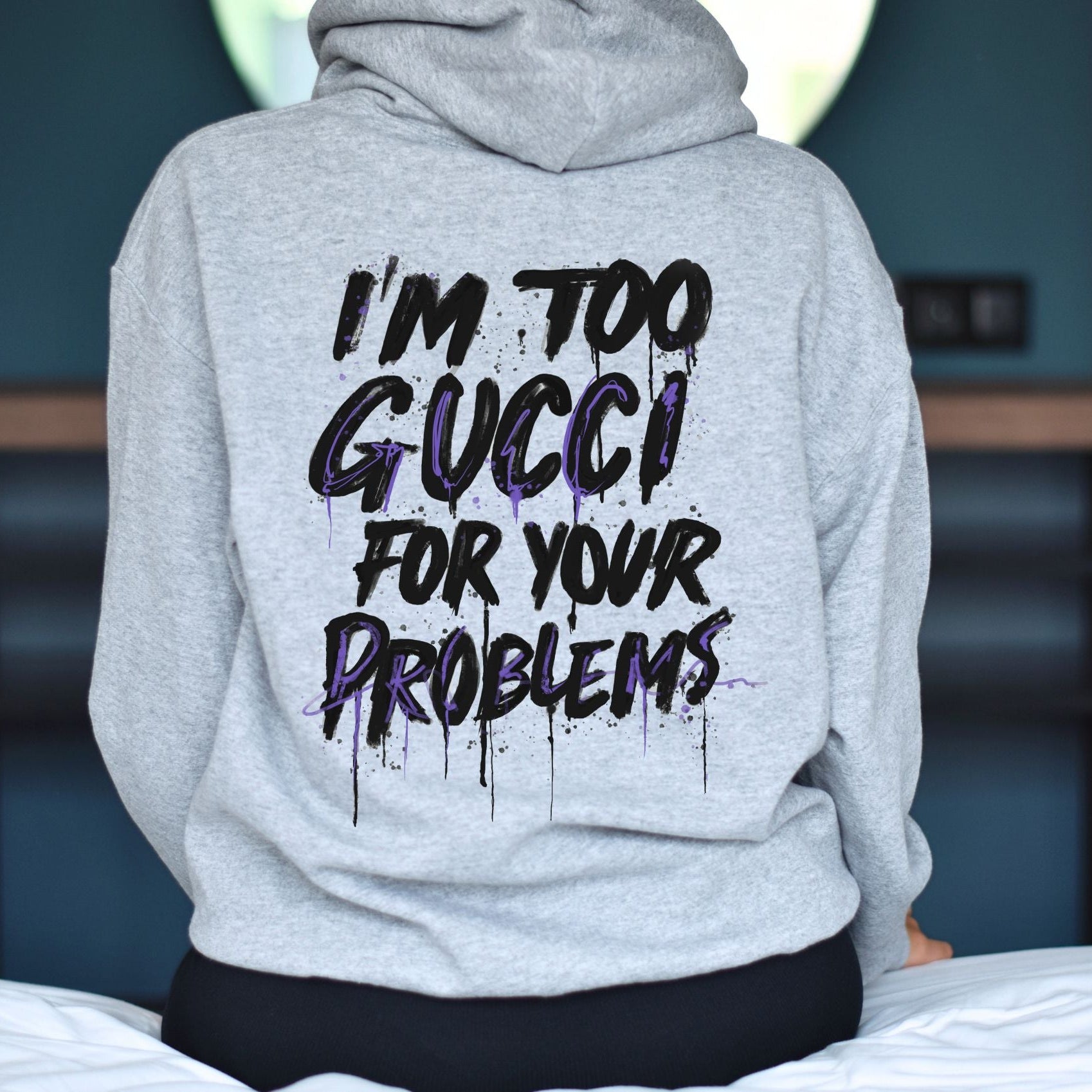 Gray hoodie with text 'I'm too Gucci for your problems' on the back, worn by a person.