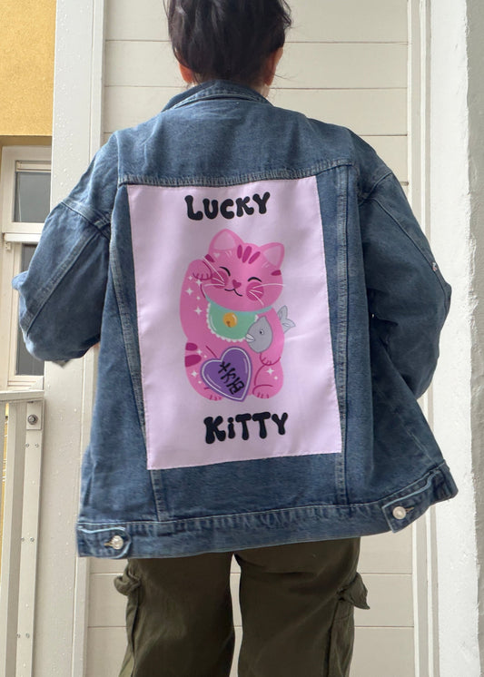 Person wearing a denim jacket with a 'Lucky Kitty' design on the back.