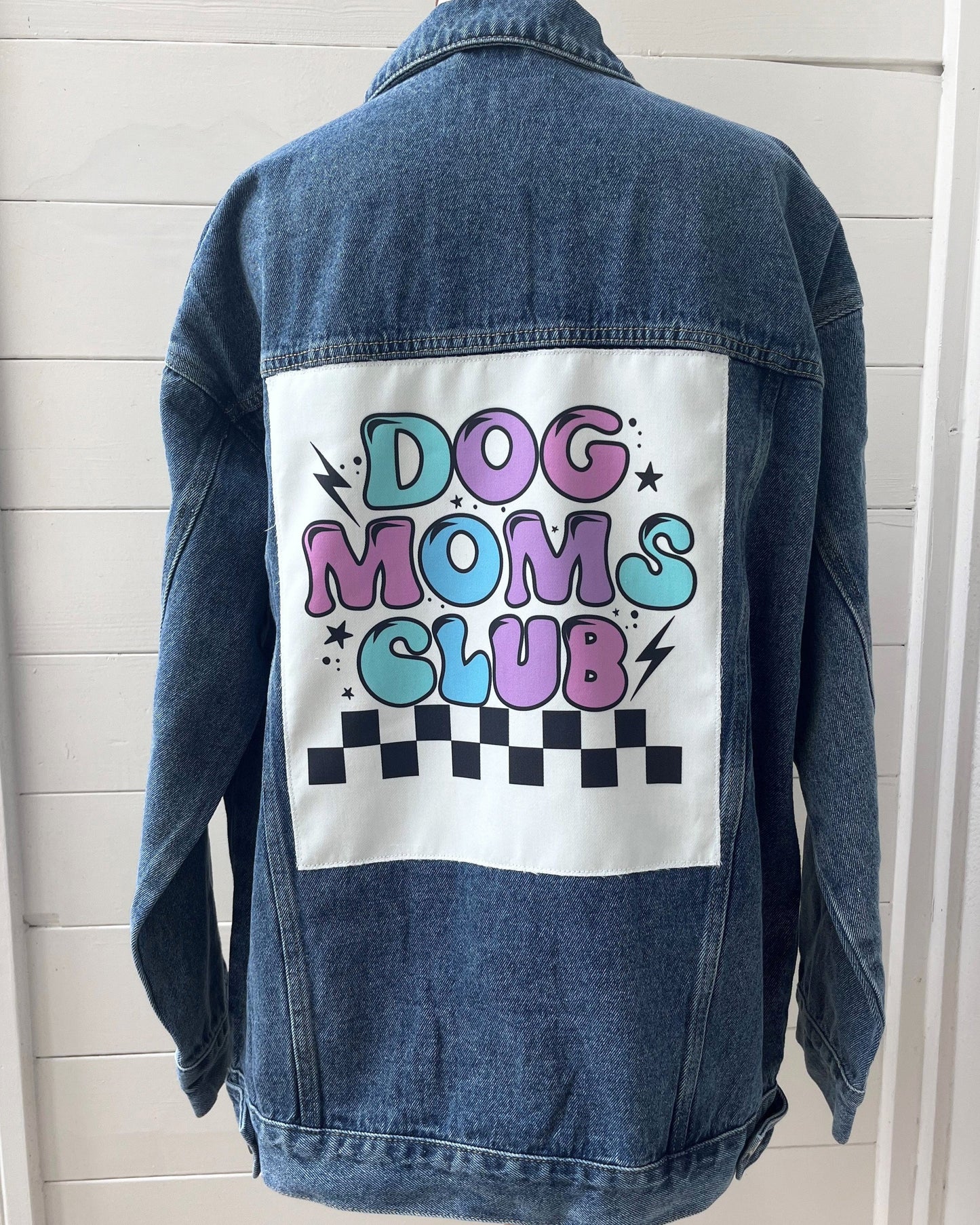 Denim jacket with 'Dog Moms Club' text on a white background