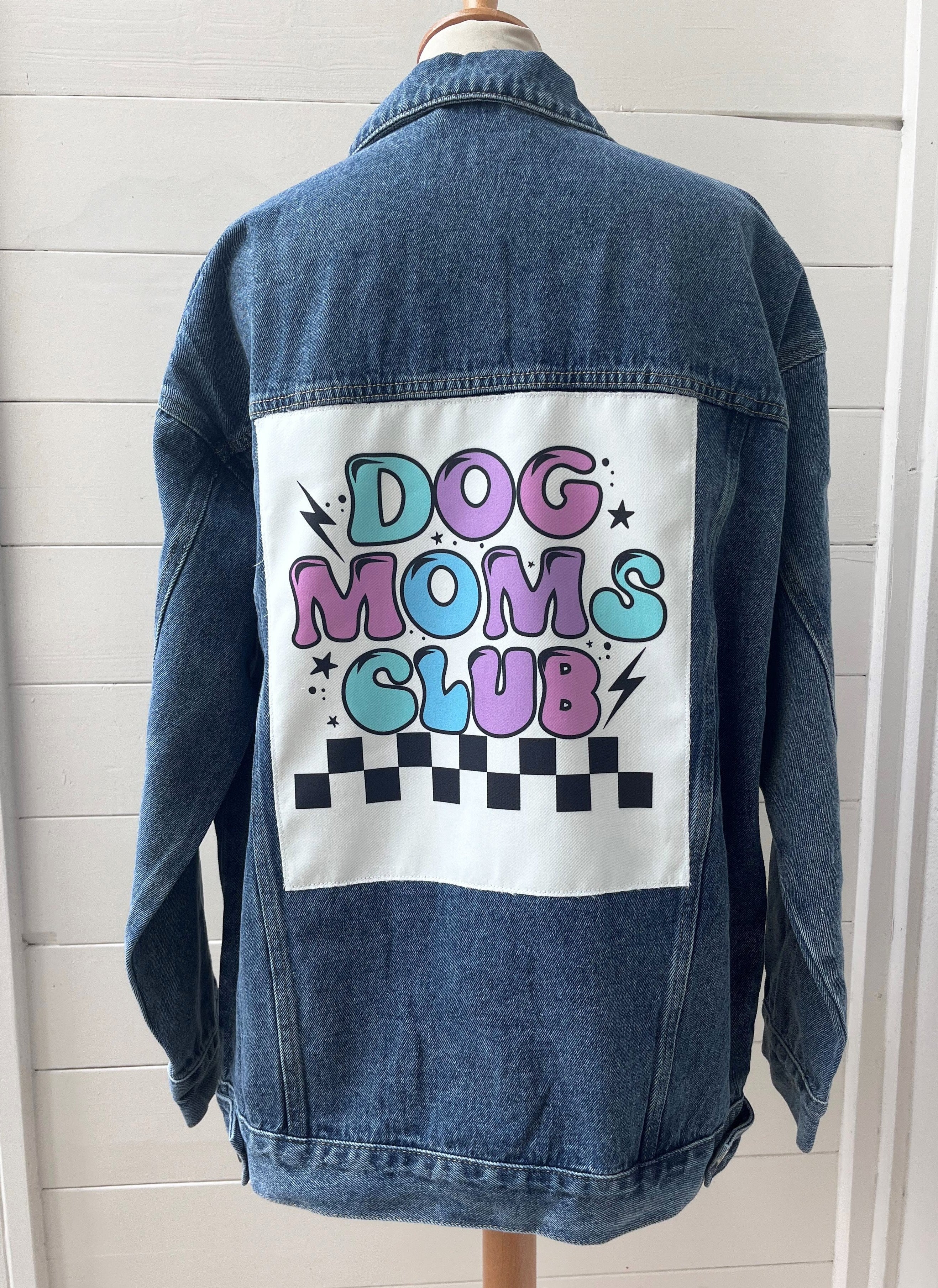 Denim jacket with 'Dog Moms Club' text on a white background
