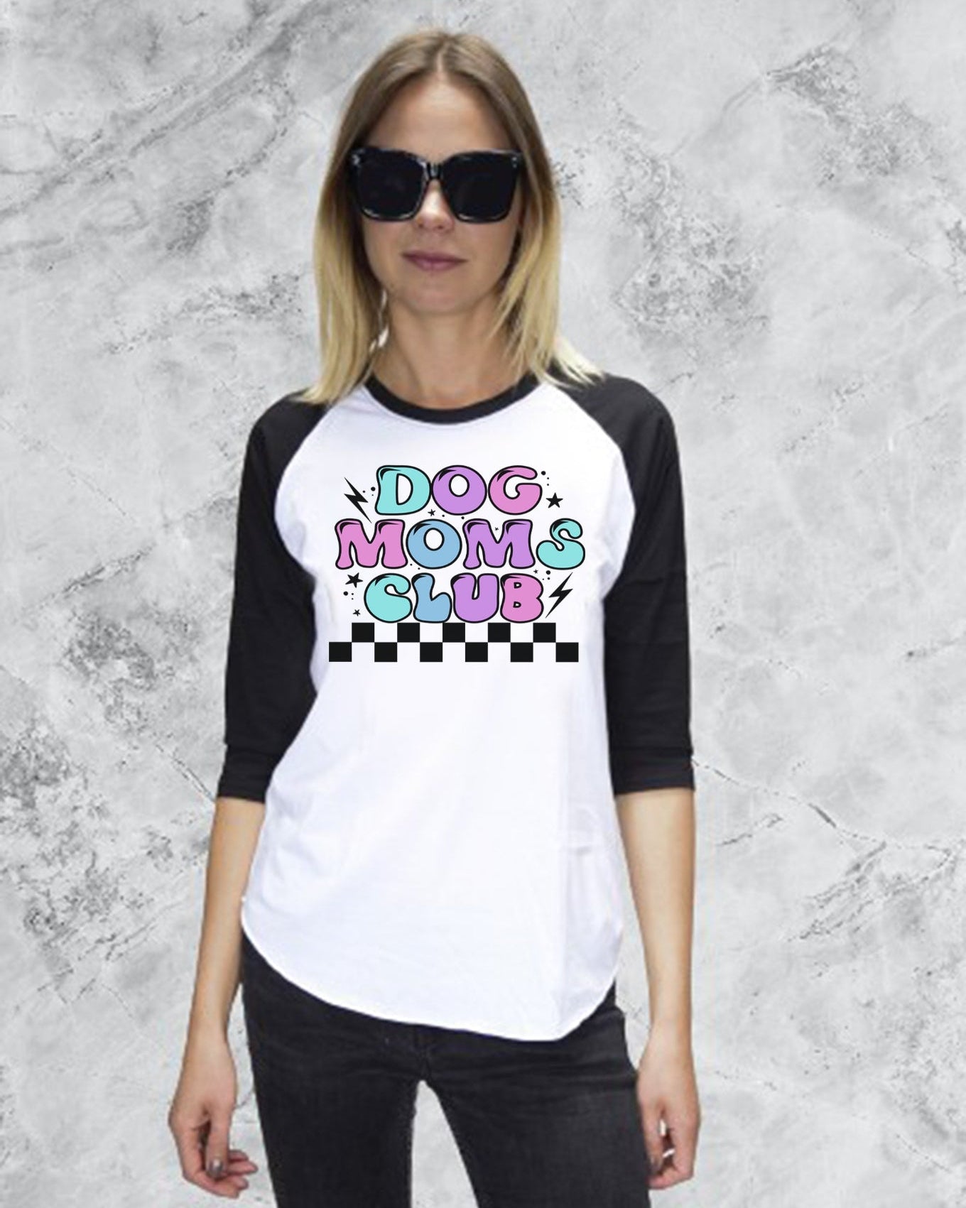 Woman wearing a black and white baseball shirt with 'Dog Moms Club' text on a gray textured background