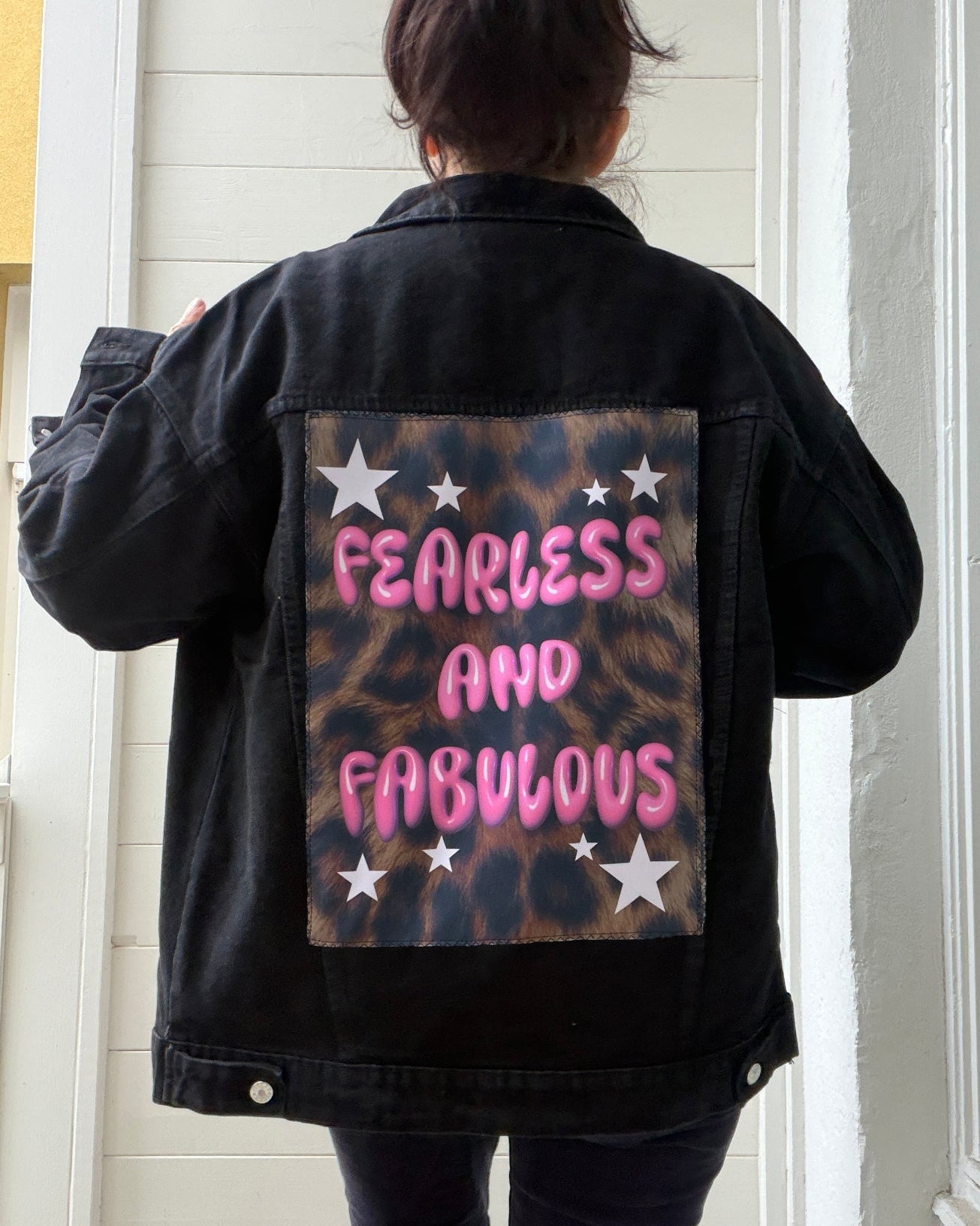 Person wearing a black jacket with 'Fearless and Fabulous' text on the back