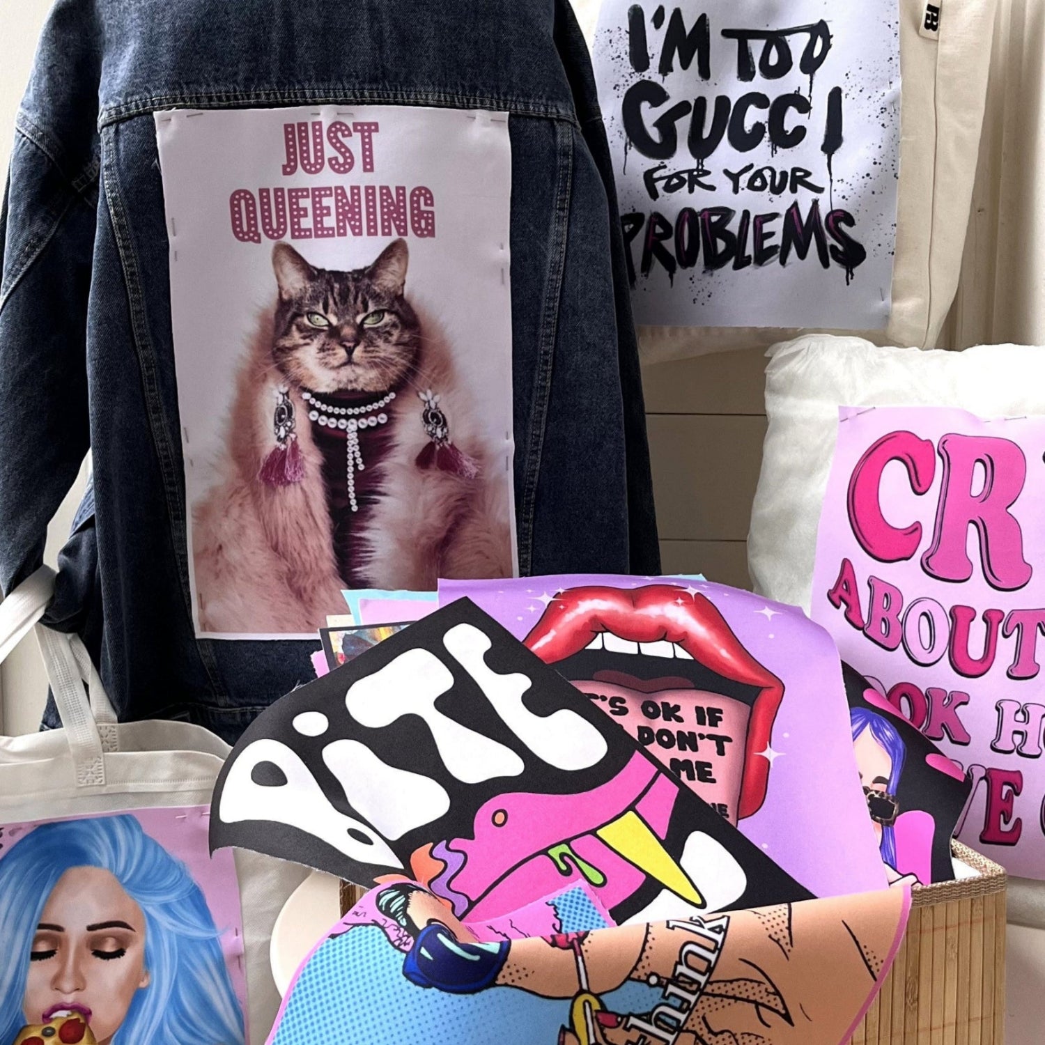 Collection of fashion accessories with graphic designs and text, including a jacket with a cat illustration and a tote bag with a colorful design.