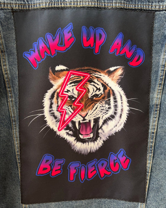 Denim jacket with a patch featuring a tiger and text 'Wake Up and Be Fierce' on a black background.