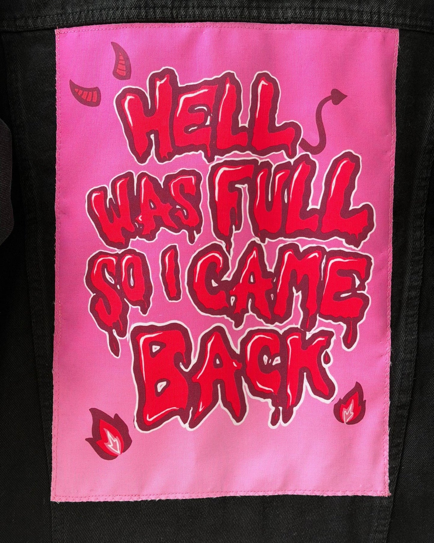 Pink patch with red text 'HELL WAS FULL SO I CAME BACK' on a black background