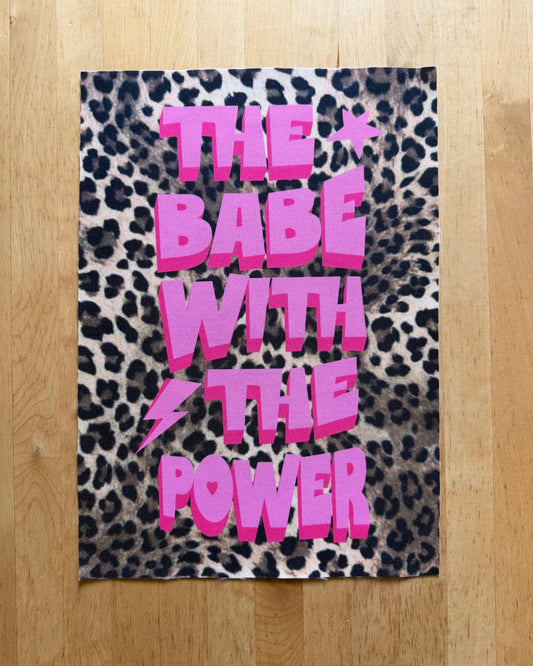 Leopard print towel with pink text on a wooden floor