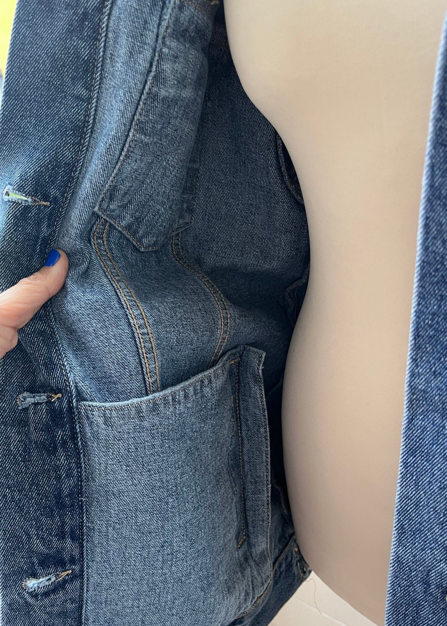 Close-up of a person wearing a blue denim jacket with a blurred background
