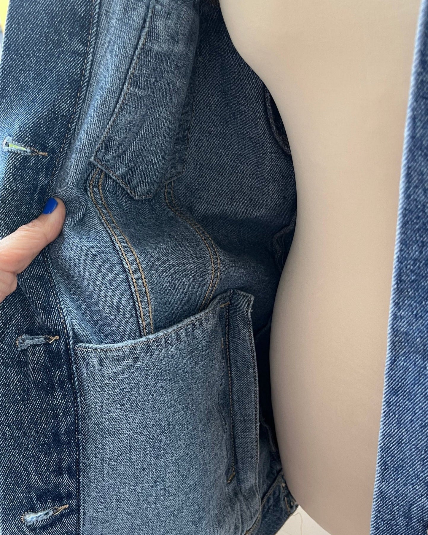 Close-up of a person wearing a blue denim jacket with a blurred background