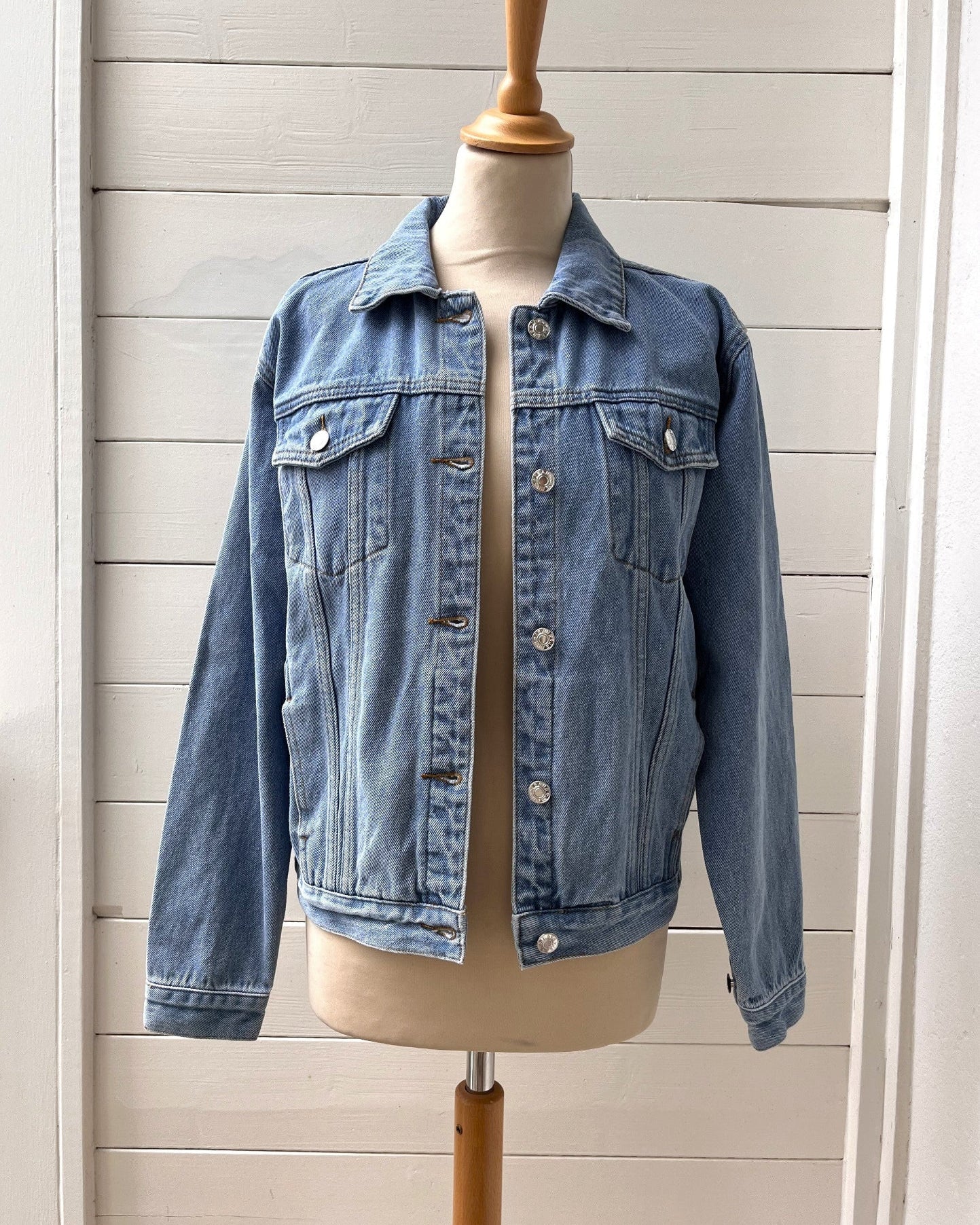 Blue denim jacket on a mannequin against a wooden panel background