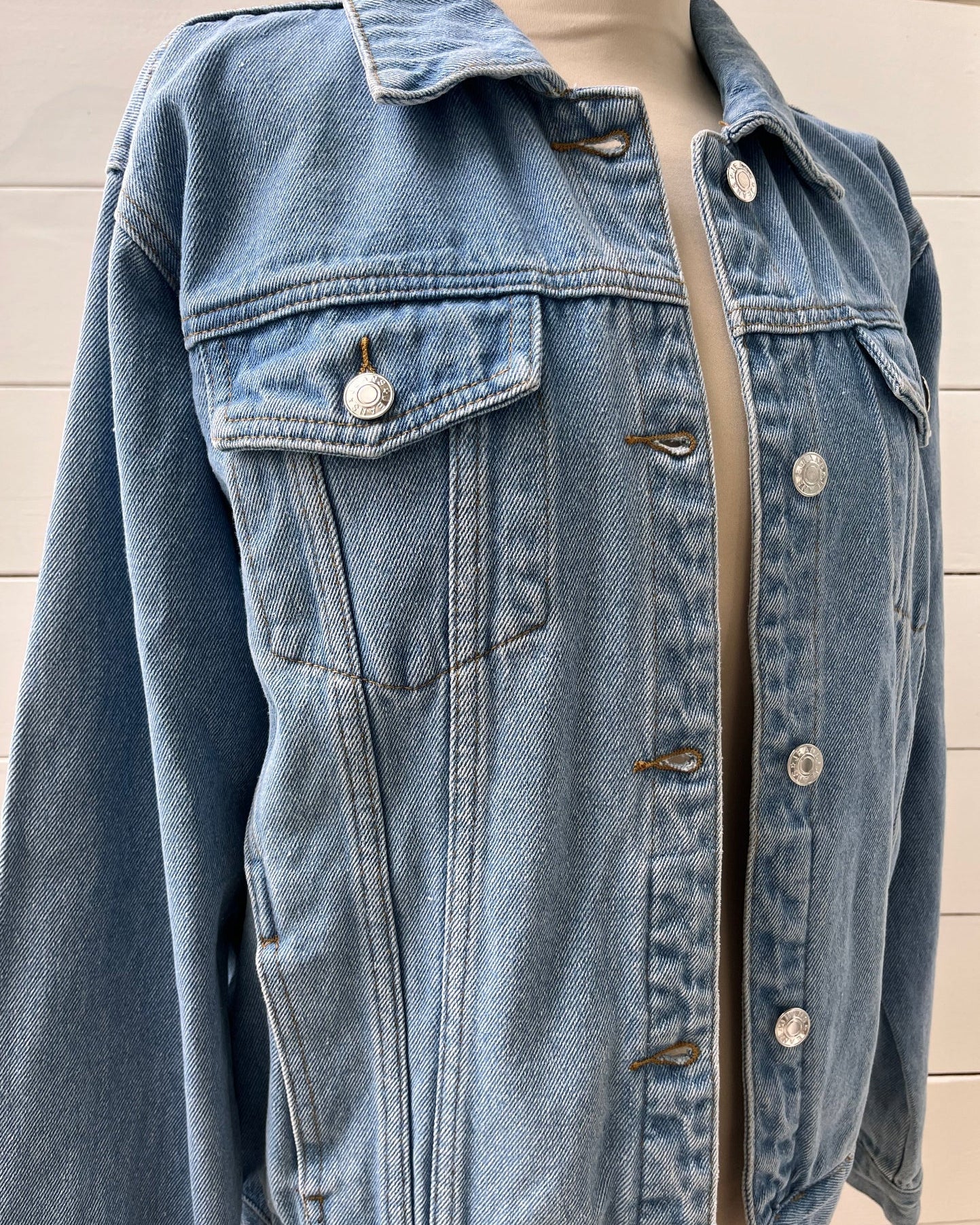 Blue denim jacket on a mannequin against a light wooden panel background