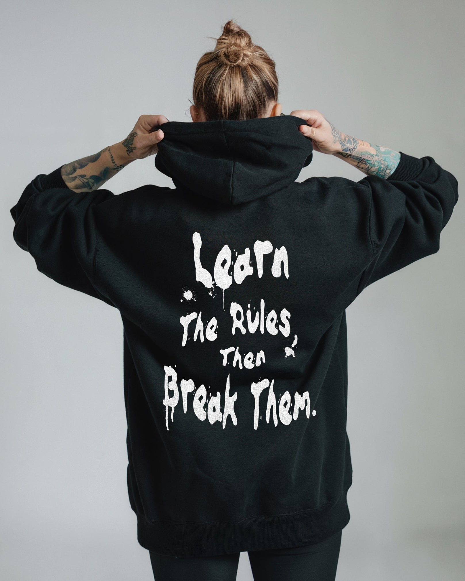 Person wearing a black hoodie with text on the back against a gray background