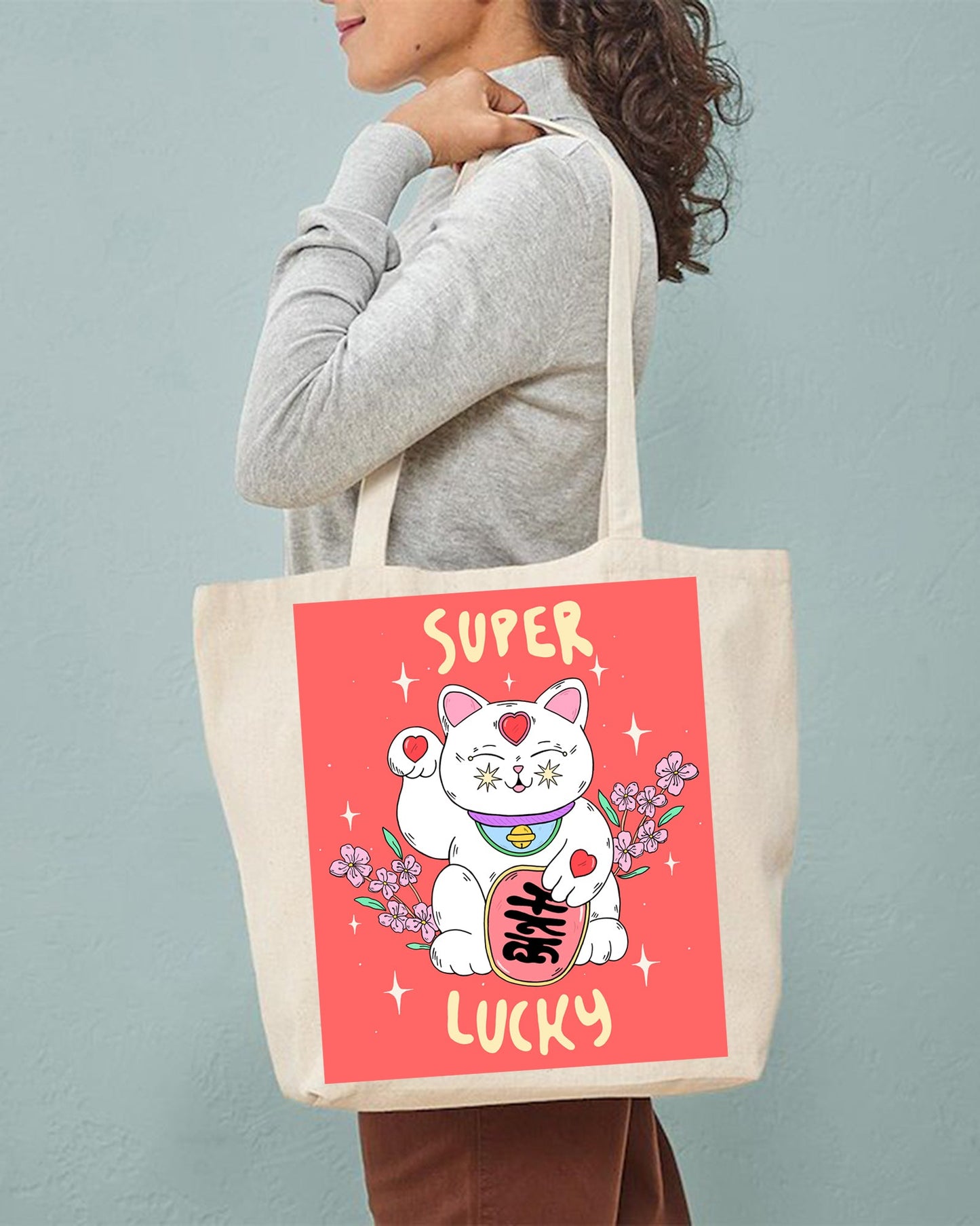 Person holding a tote bag with a cartoon cat design and 'Super Lucky' text on a red background.