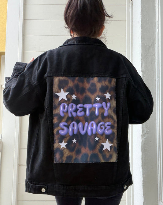 Person wearing a black jacket with 'Pretty Savage' text and leopard print design.