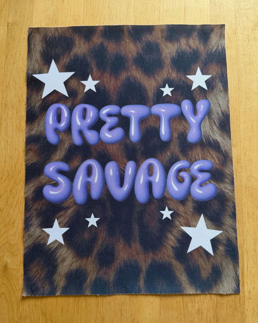 Leopard print fabric with 'Pretty Savage' text and stars on a wooden surface