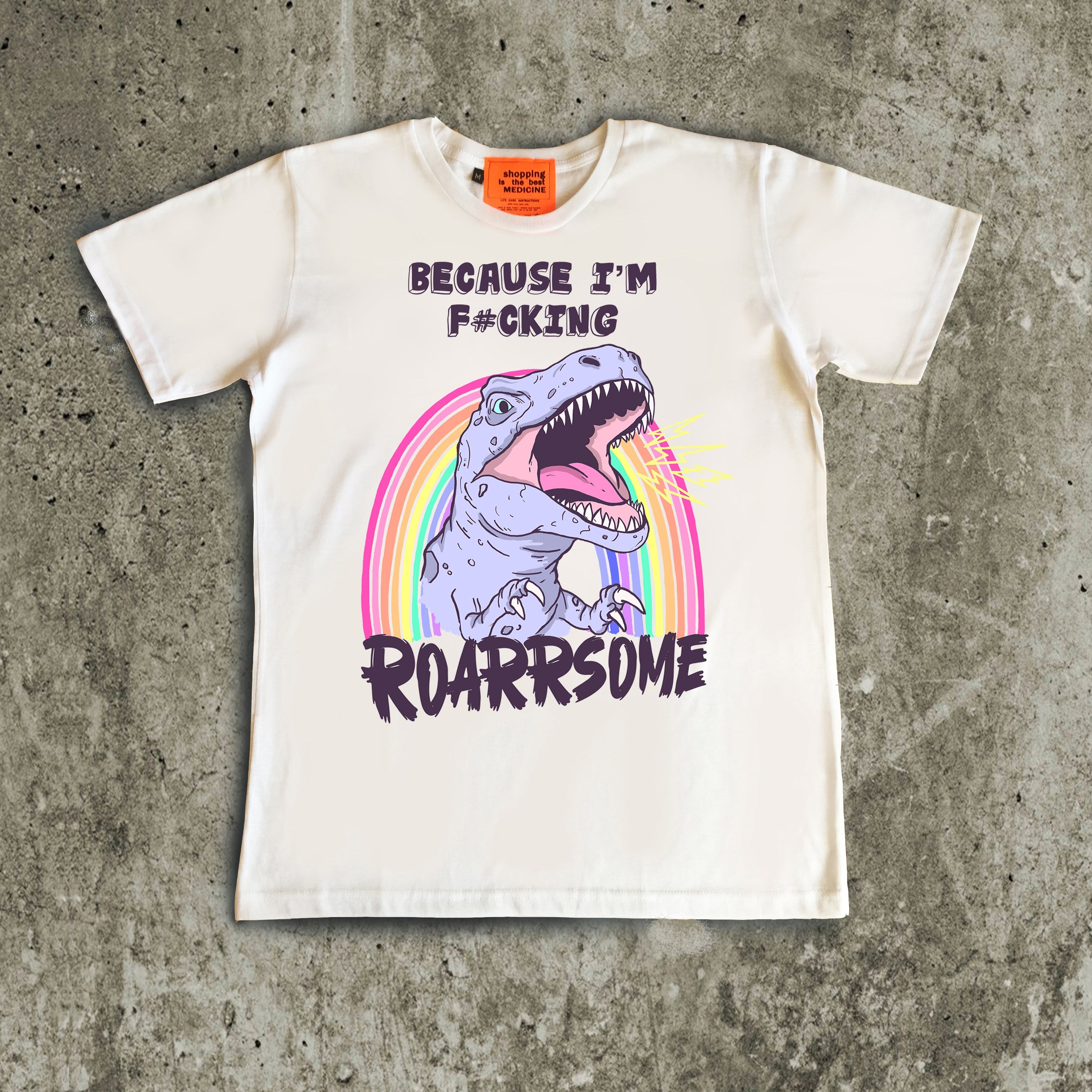 White t-shirt with dinosaur graphic and text on a concrete surface