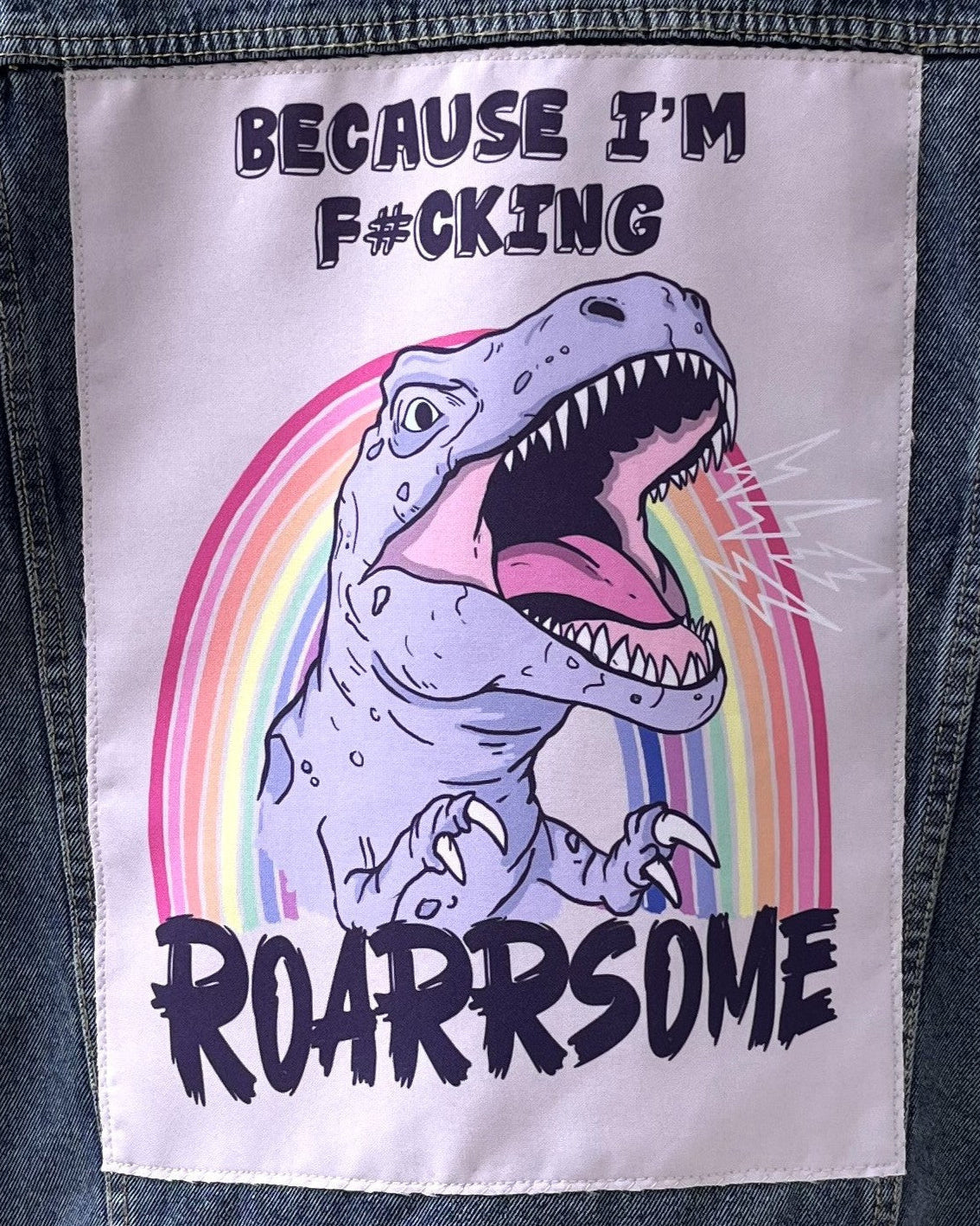 Patch with a dinosaur and rainbow design on a denim jacket