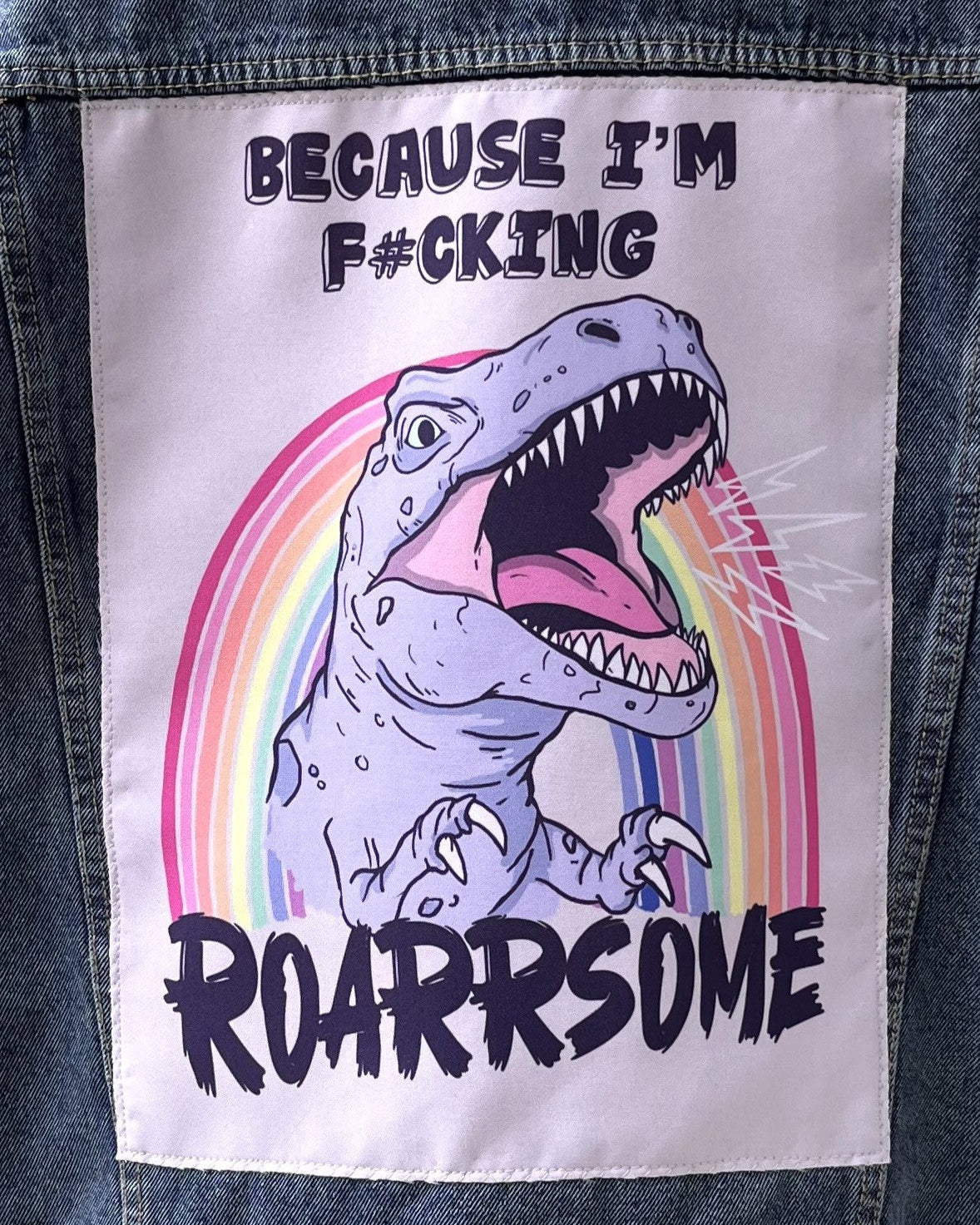 Patch with a dinosaur illustration and text on a denim background
