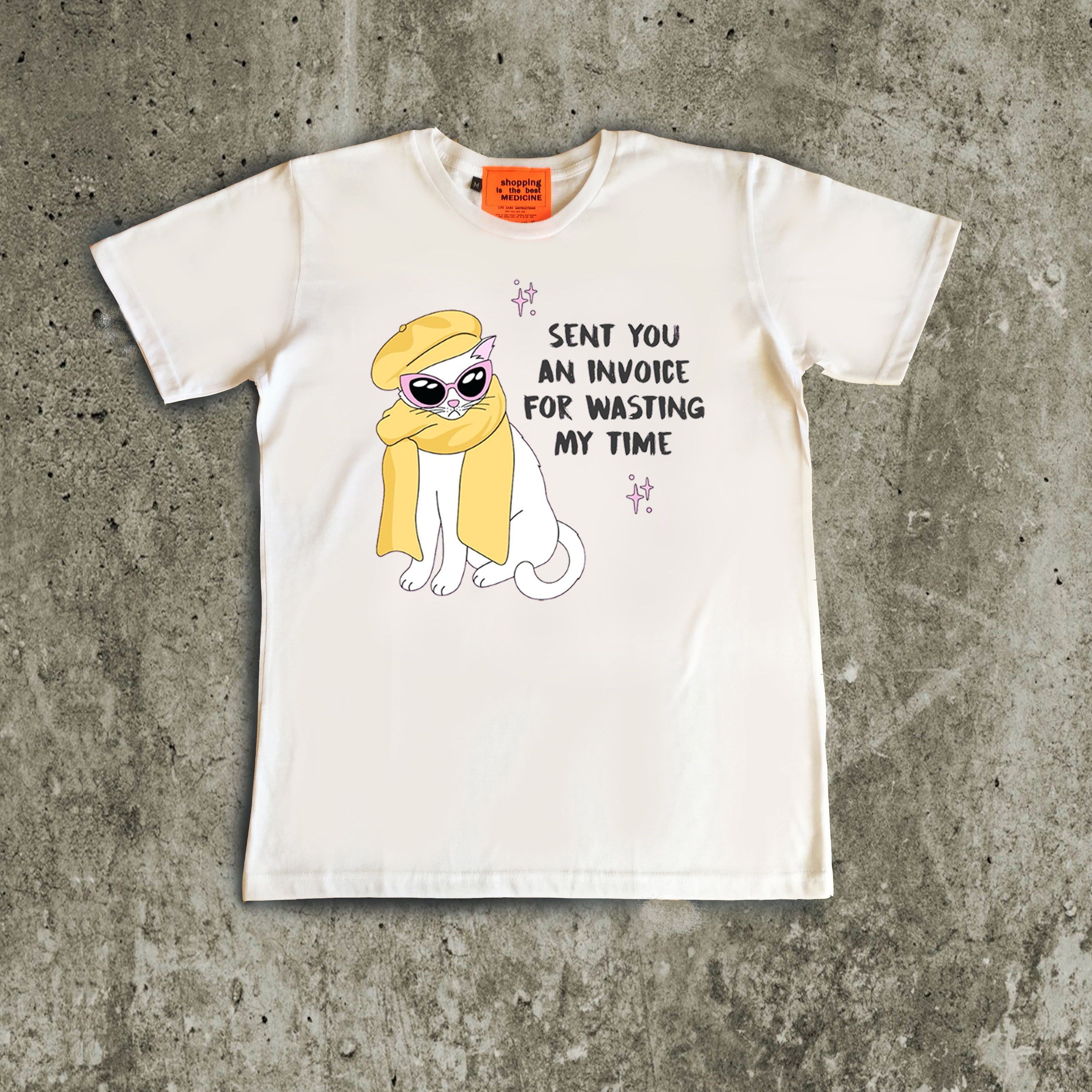 White t-shirt with a cartoon character and text on a concrete surface