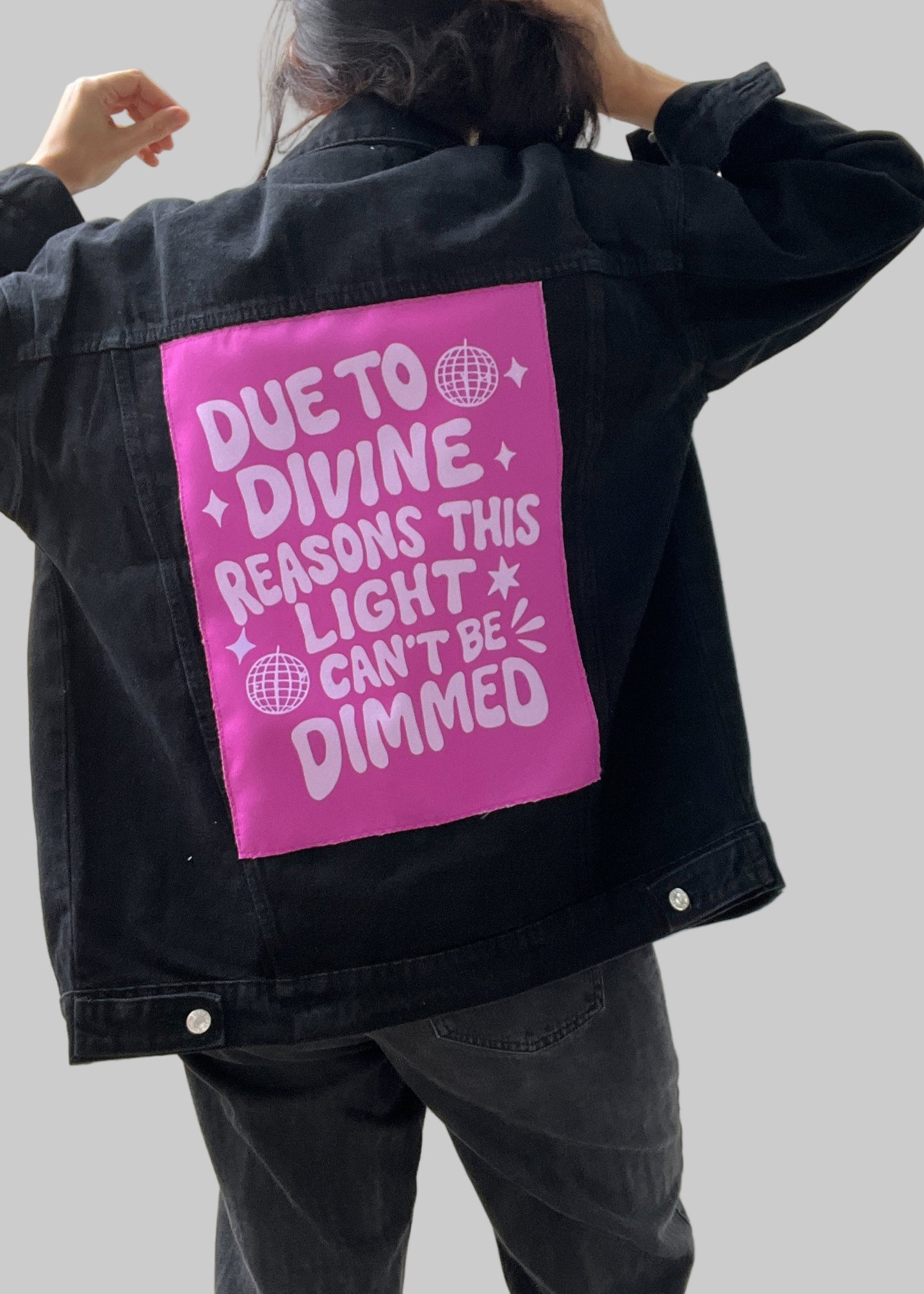 Person wearing a black jacket with a pink patch on the back