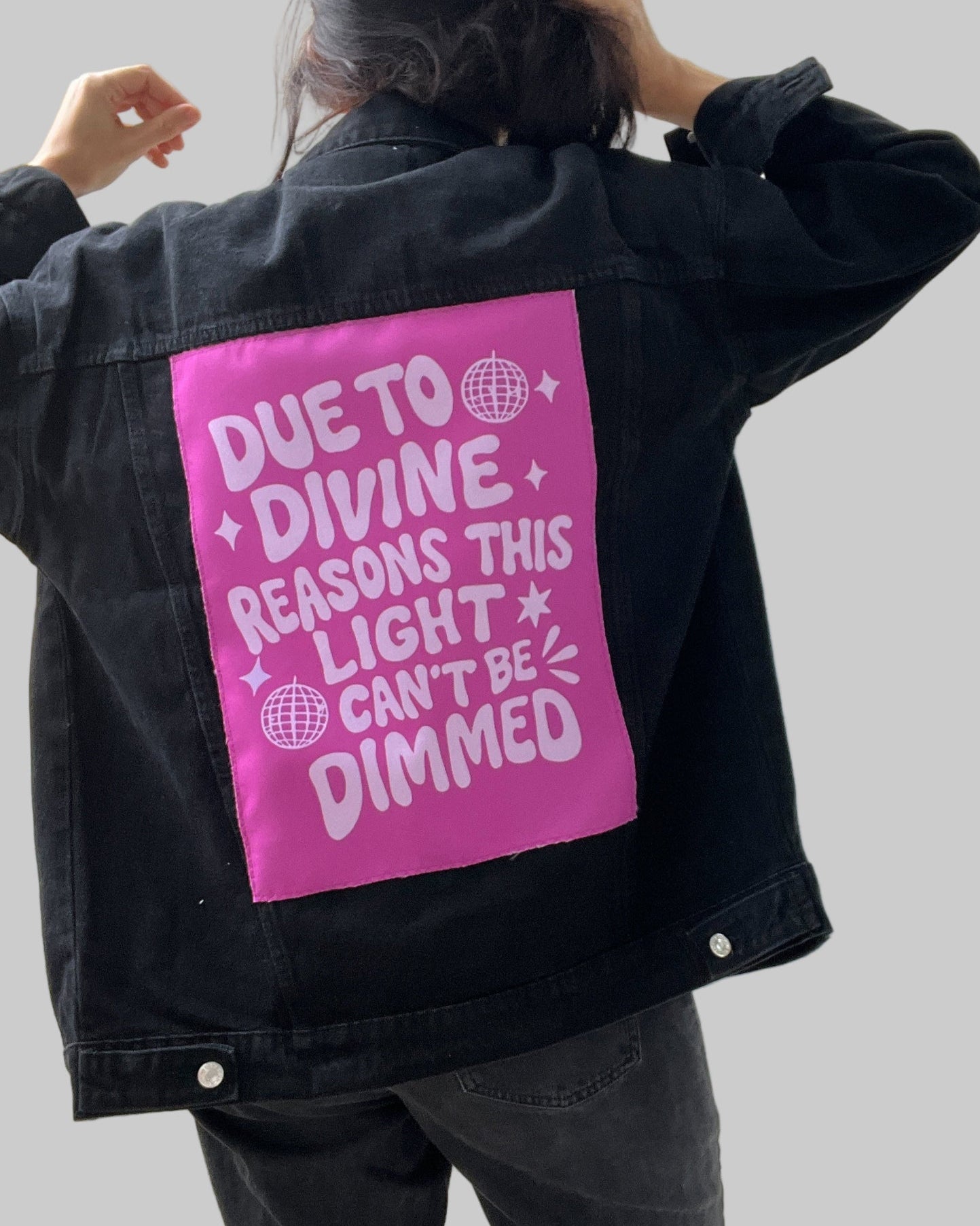 Person wearing a black jacket with a pink patch on the back