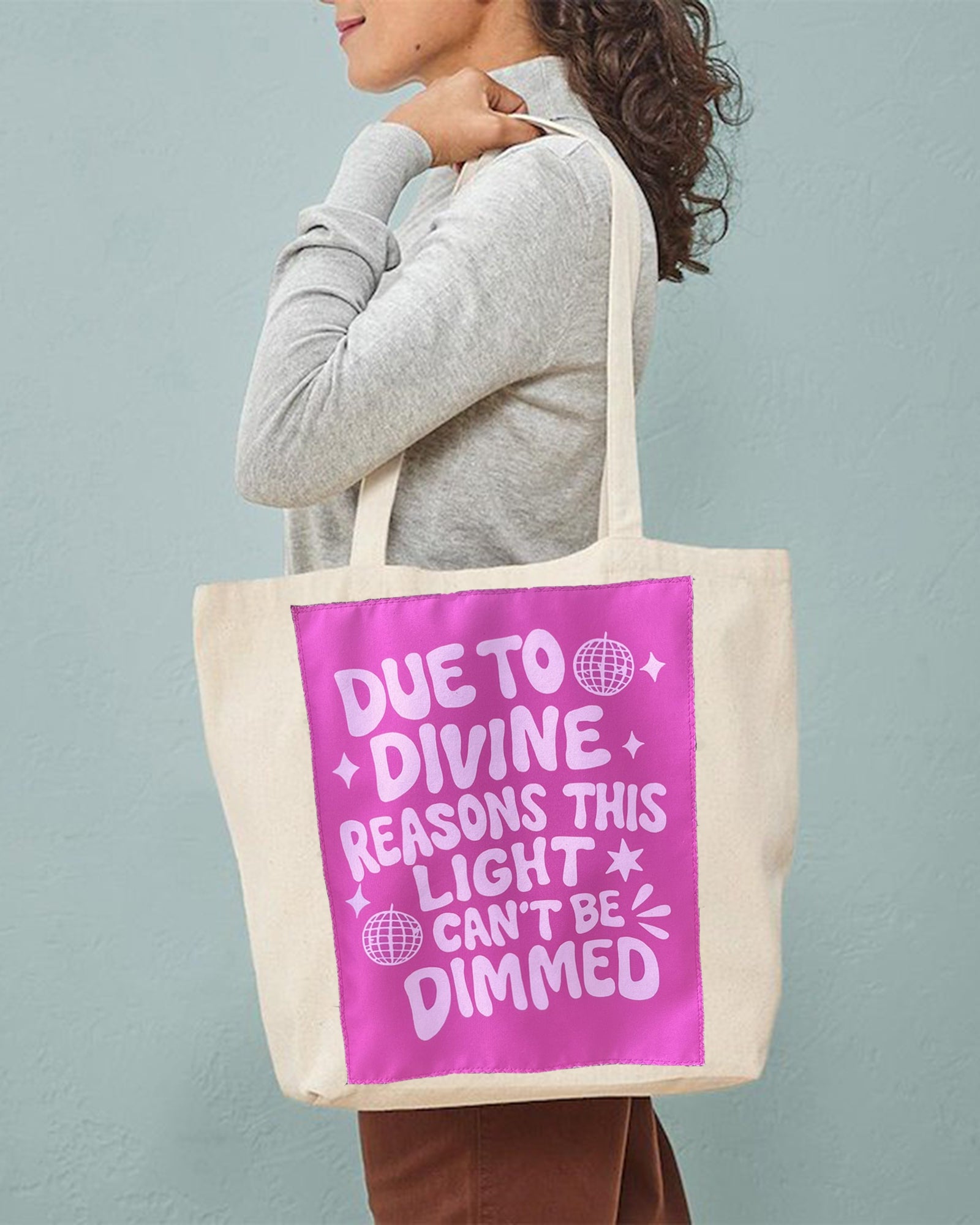 Person holding a tote bag with a pink message against a gray background