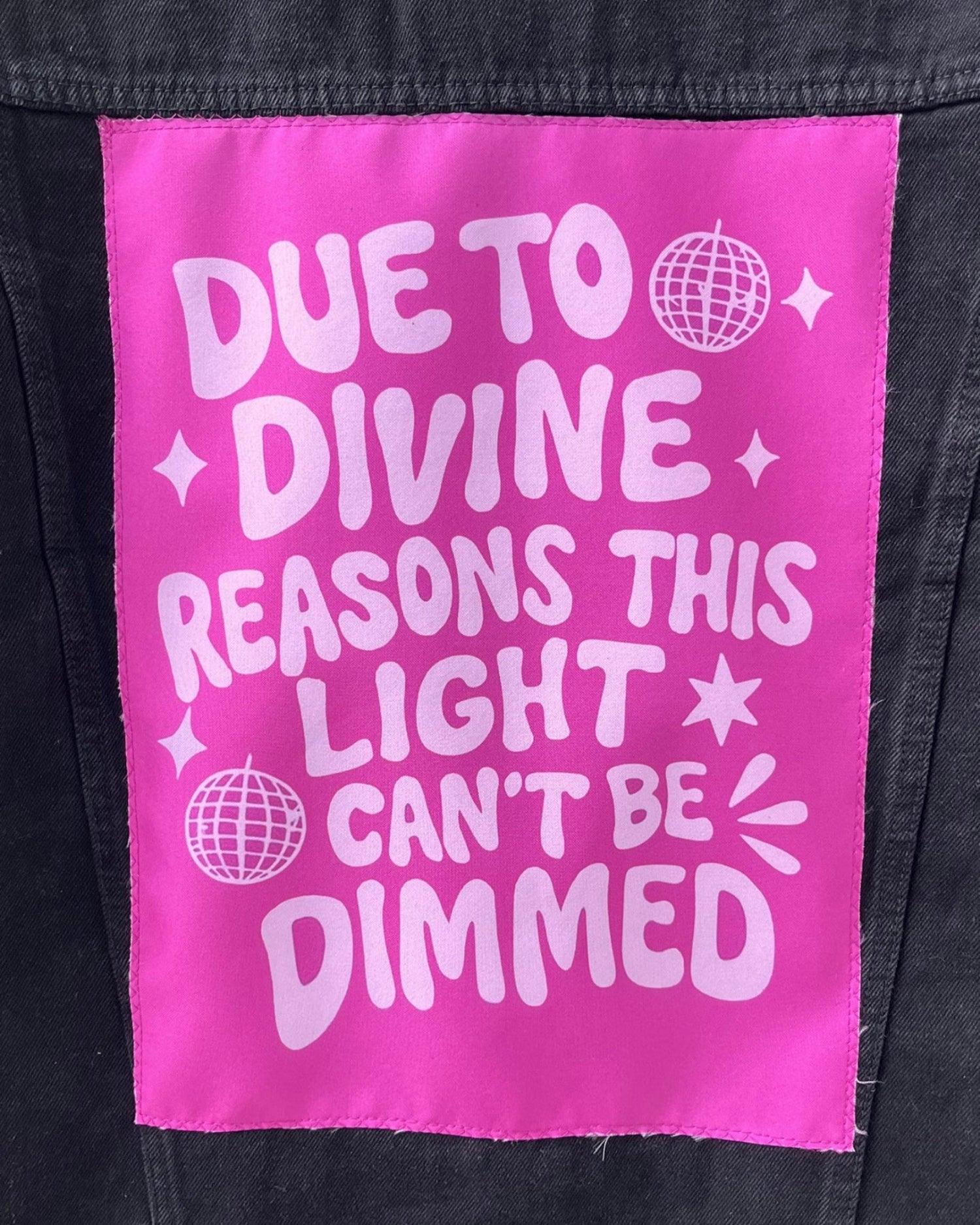 Pink patch with white text on a black denim background