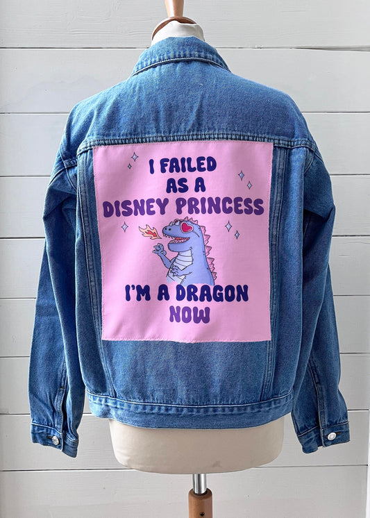 Blue denim jacket with a pink patch featuring text and a dragon illustration on a white background