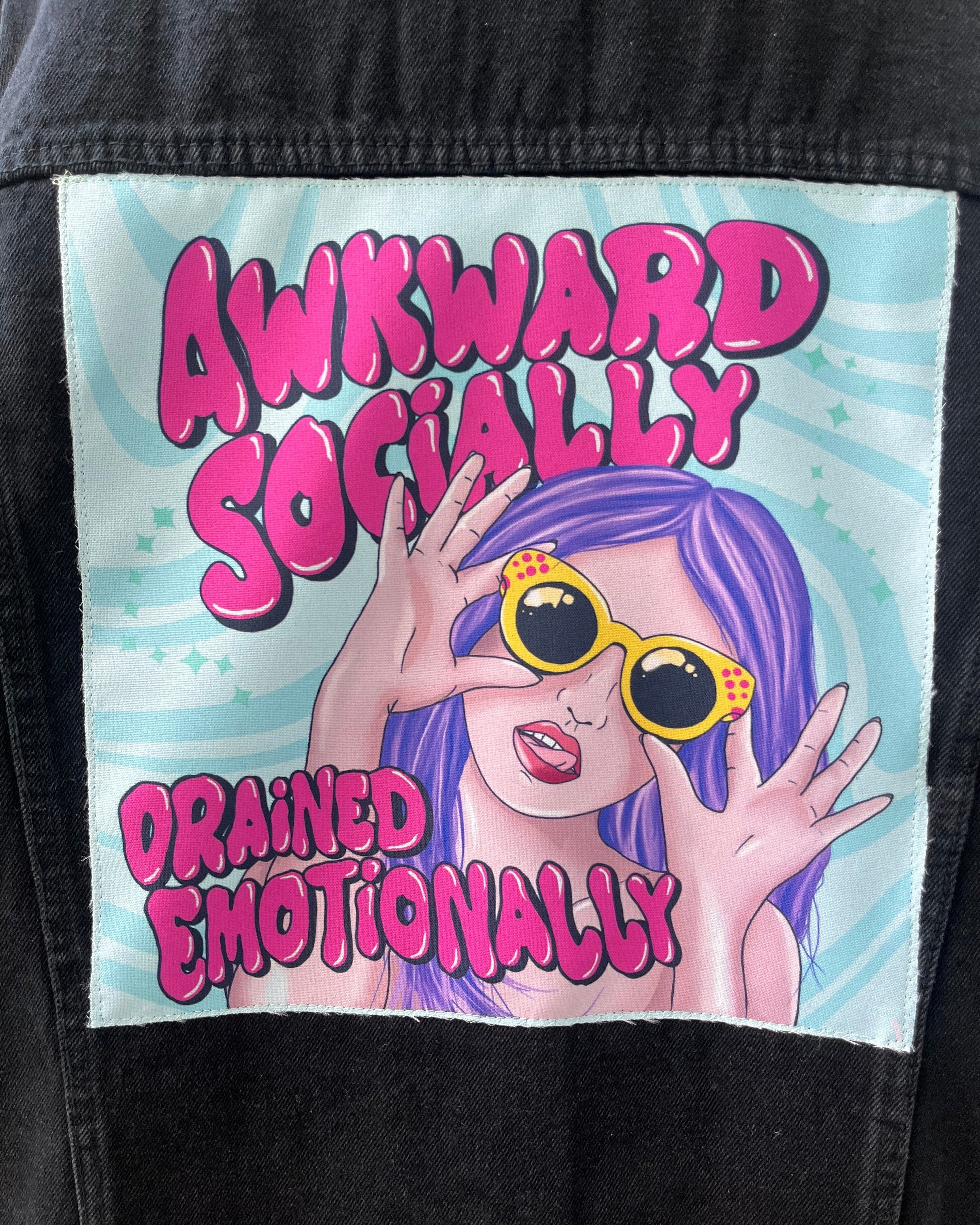 Patch on a jacket with colorful text and an illustration of a person with purple hair and sunglasses.
