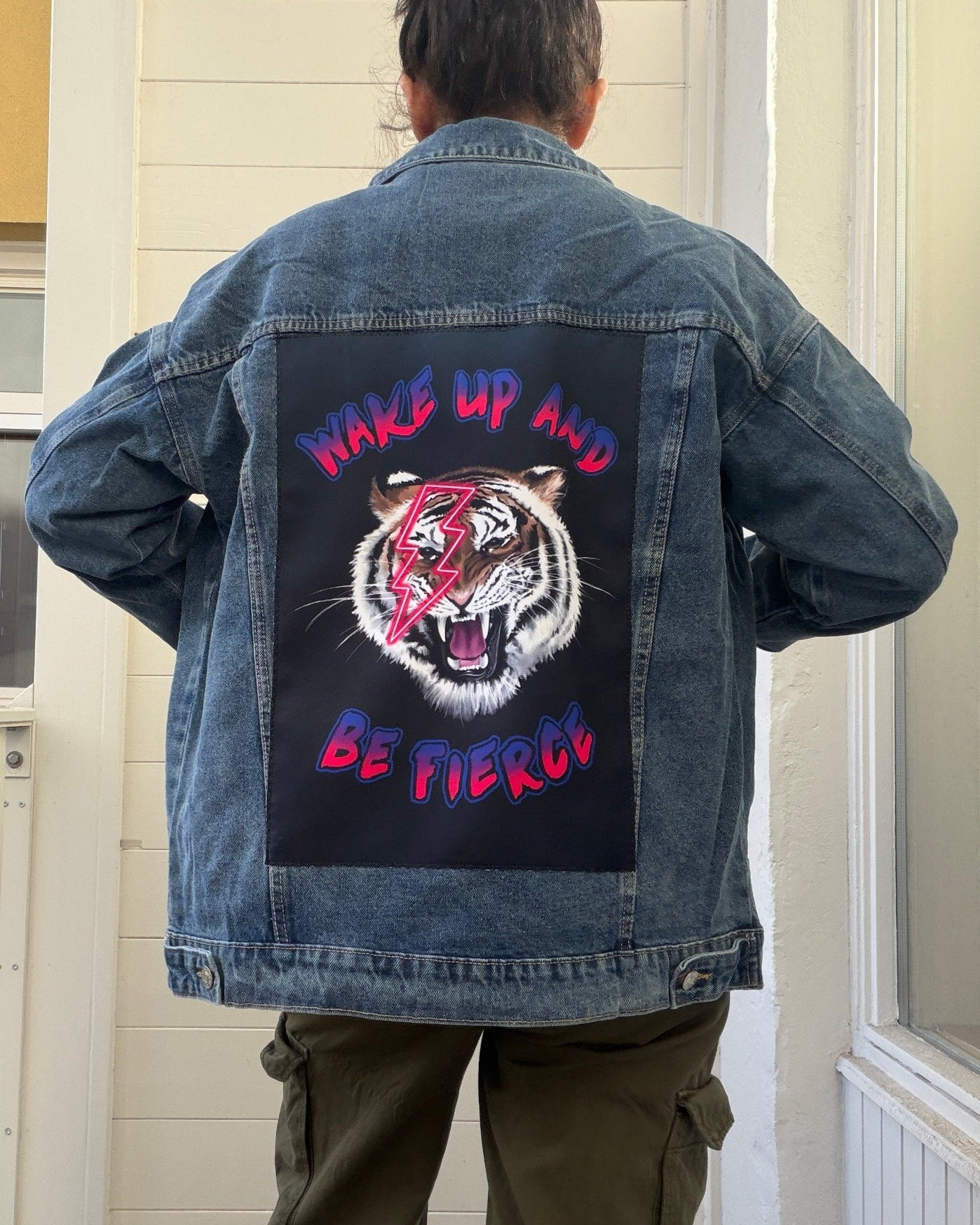 Person wearing a denim jacket with a graphic design and text on the back.