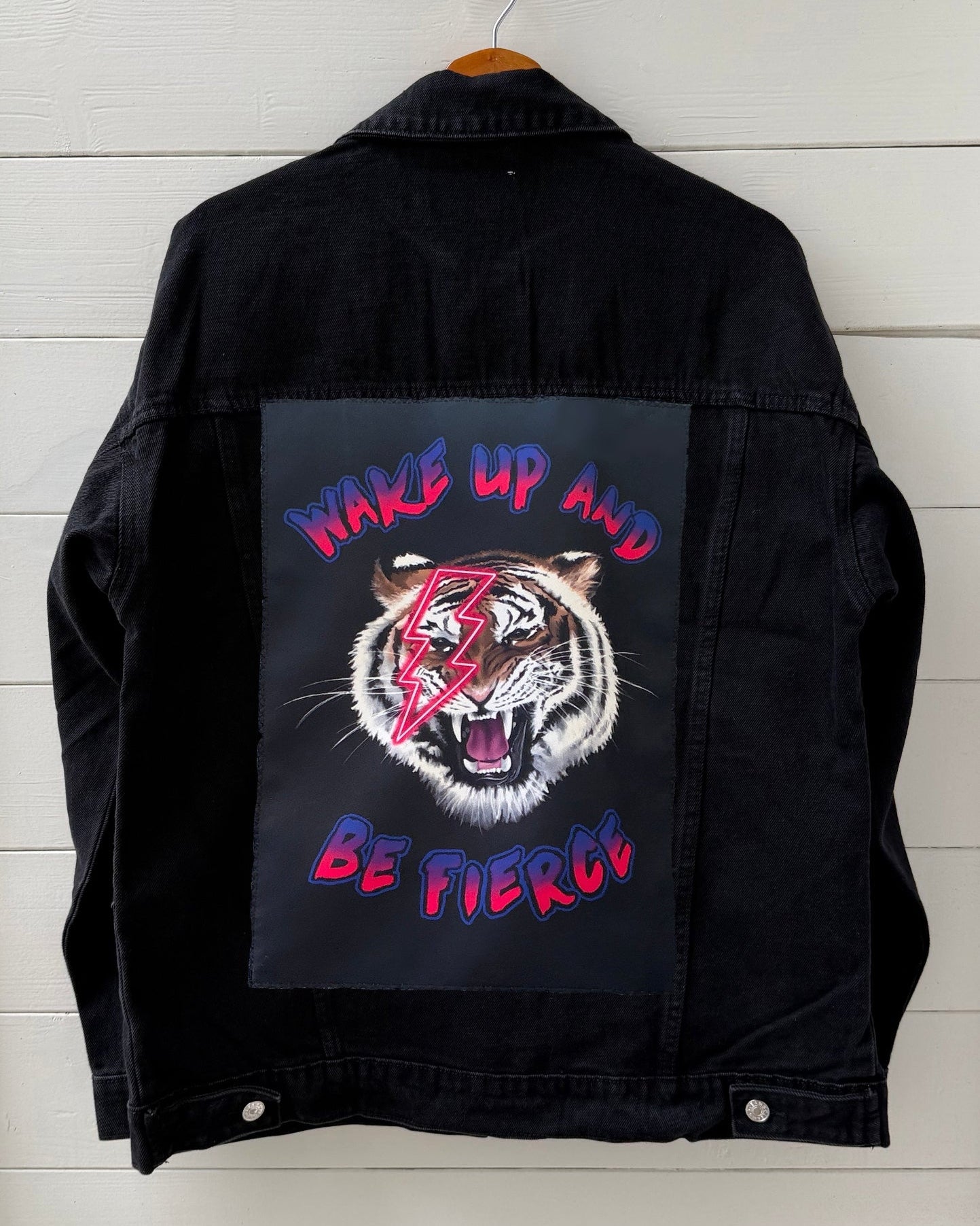 Black jacket with a graphic of a tiger and text on a wooden background