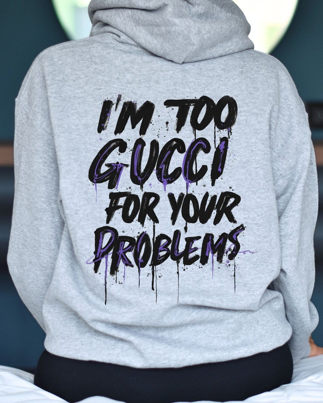 Gray hoodie with text 'I'm too Gucci for your problems' on the back, worn by a person.