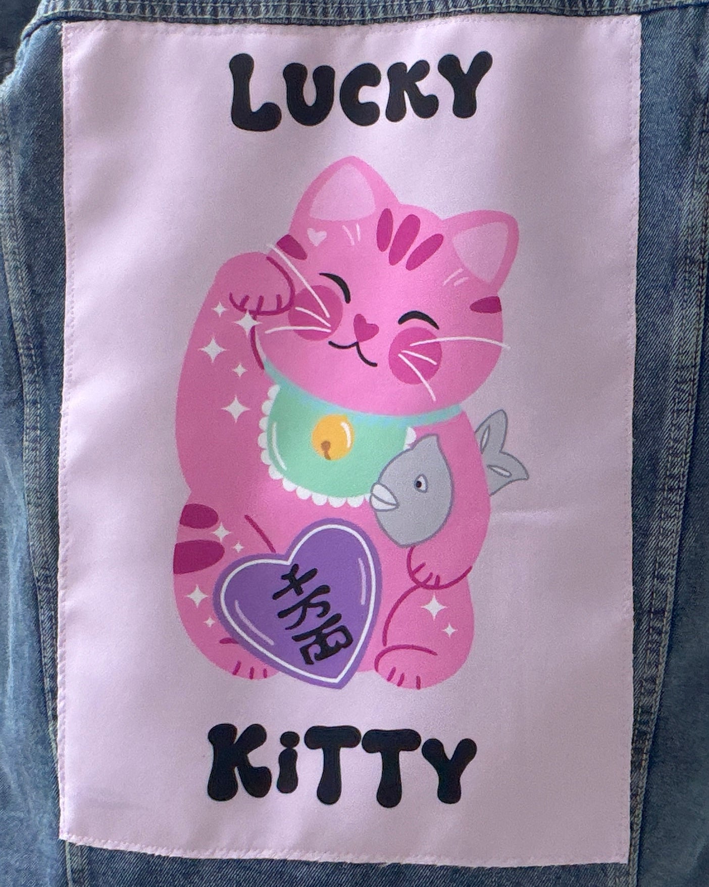 Pink cartoon cat with a fish and text on a denim jacket