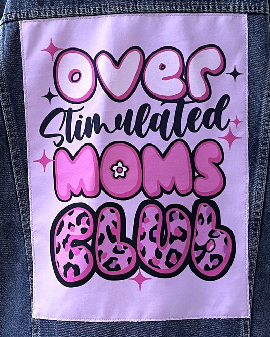 Denim jacket with a patch reading 'Over Stimulated Moms Club' in pink and black text.