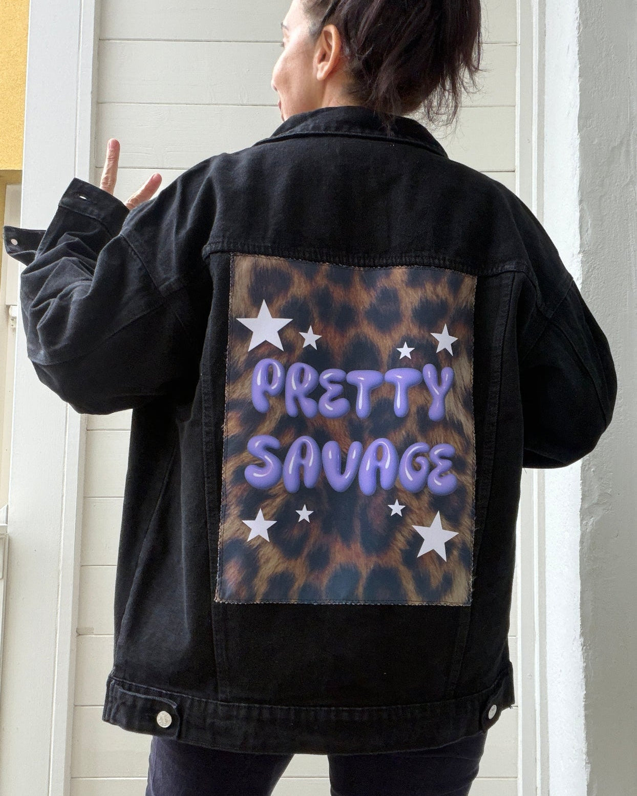 Person wearing a black jacket with 'Pretty Savage' design on the back