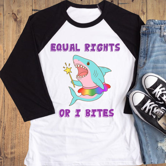 Raglan shirt with shark graphic and text, paired with jeans and sneakers on a wooden surface